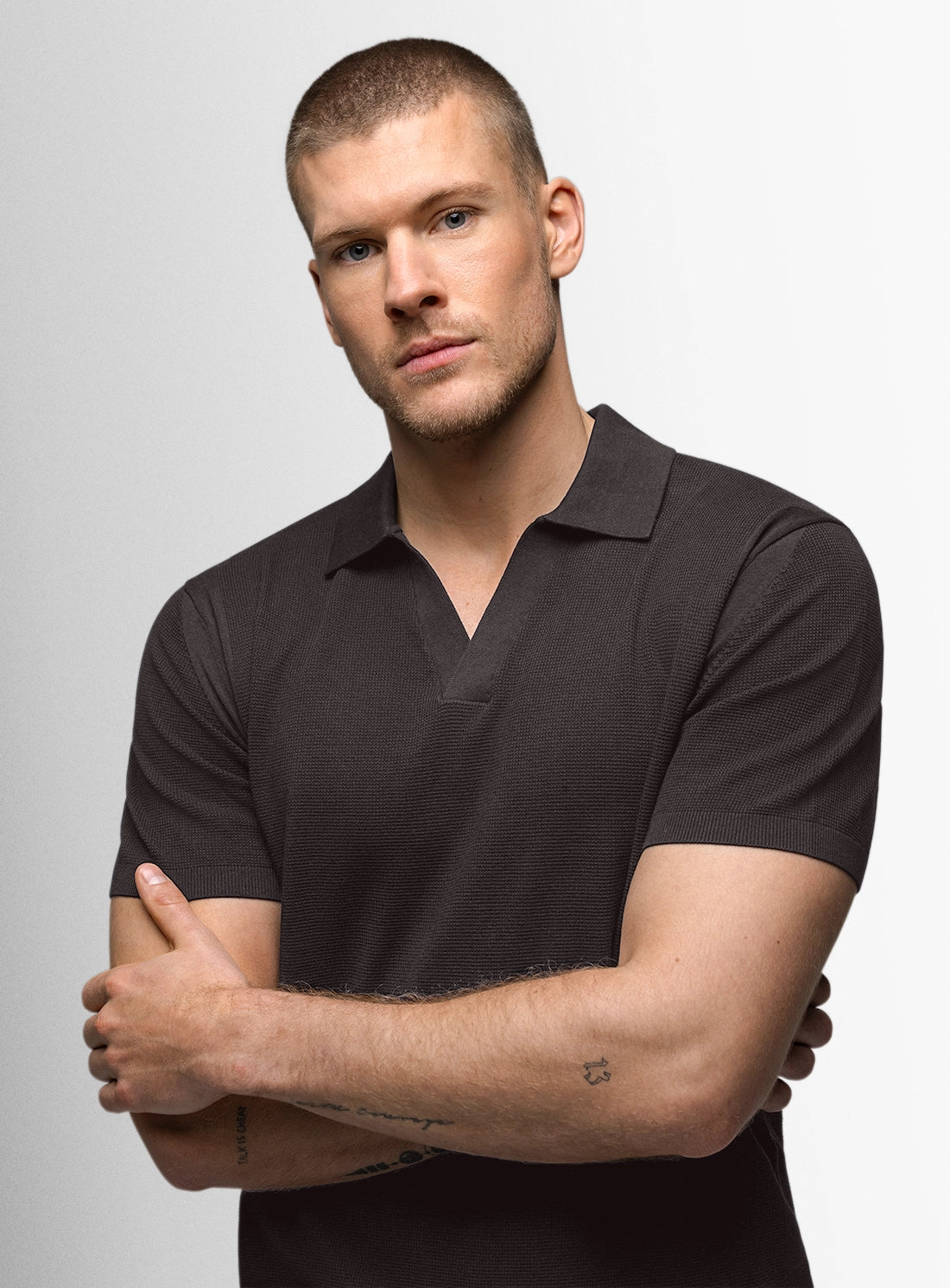 Man wearing a black polo shirt against a gray background