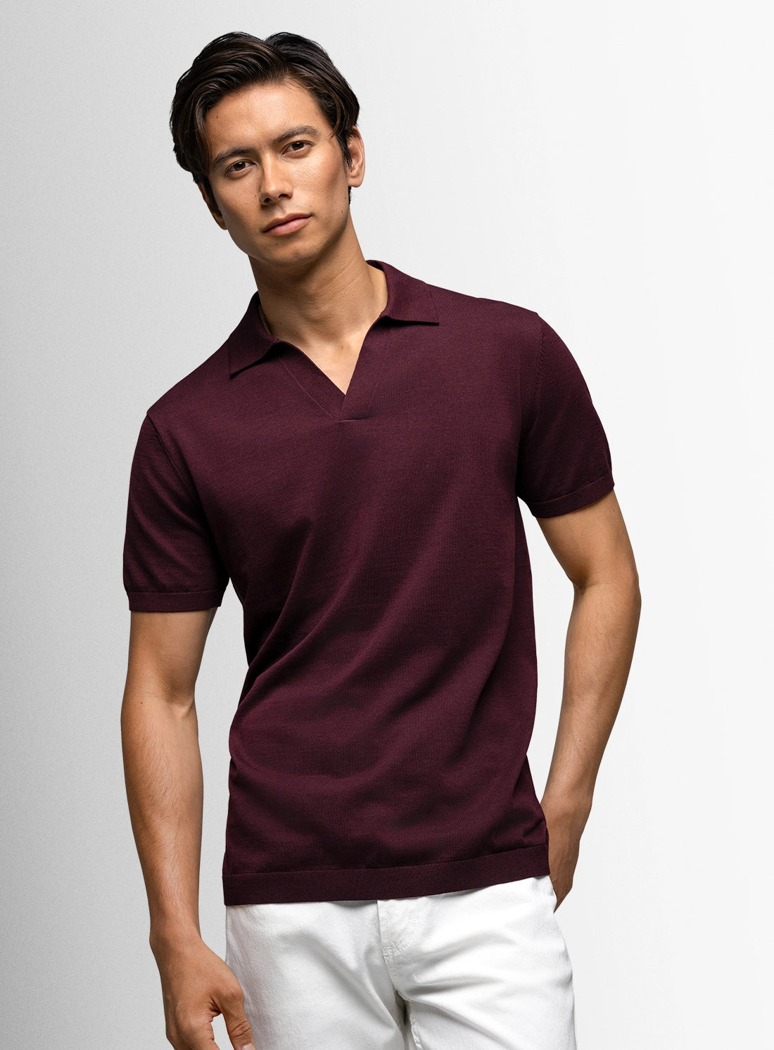 Man wearing a maroon polo shirt against a gray background