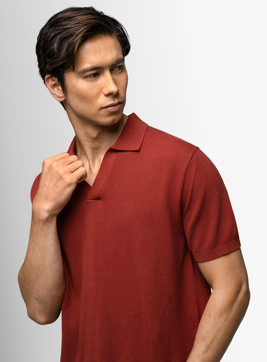 Man wearing a red polo shirt against a gray background
