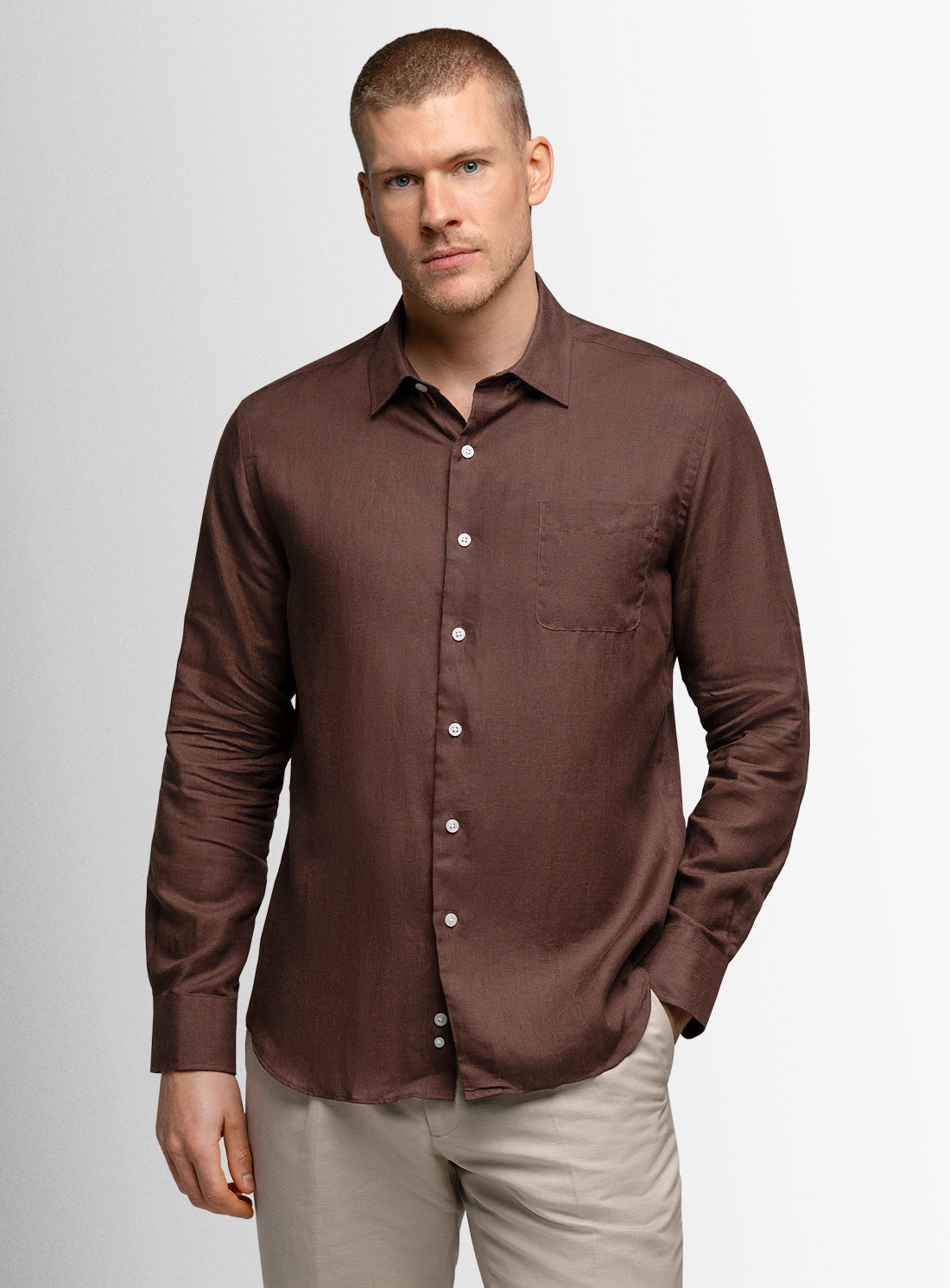 Man wearing a brown button-up shirt against a plain background