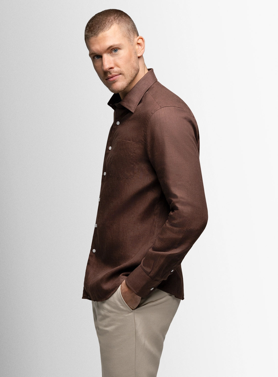 Man wearing a brown shirt and beige pants on a white background