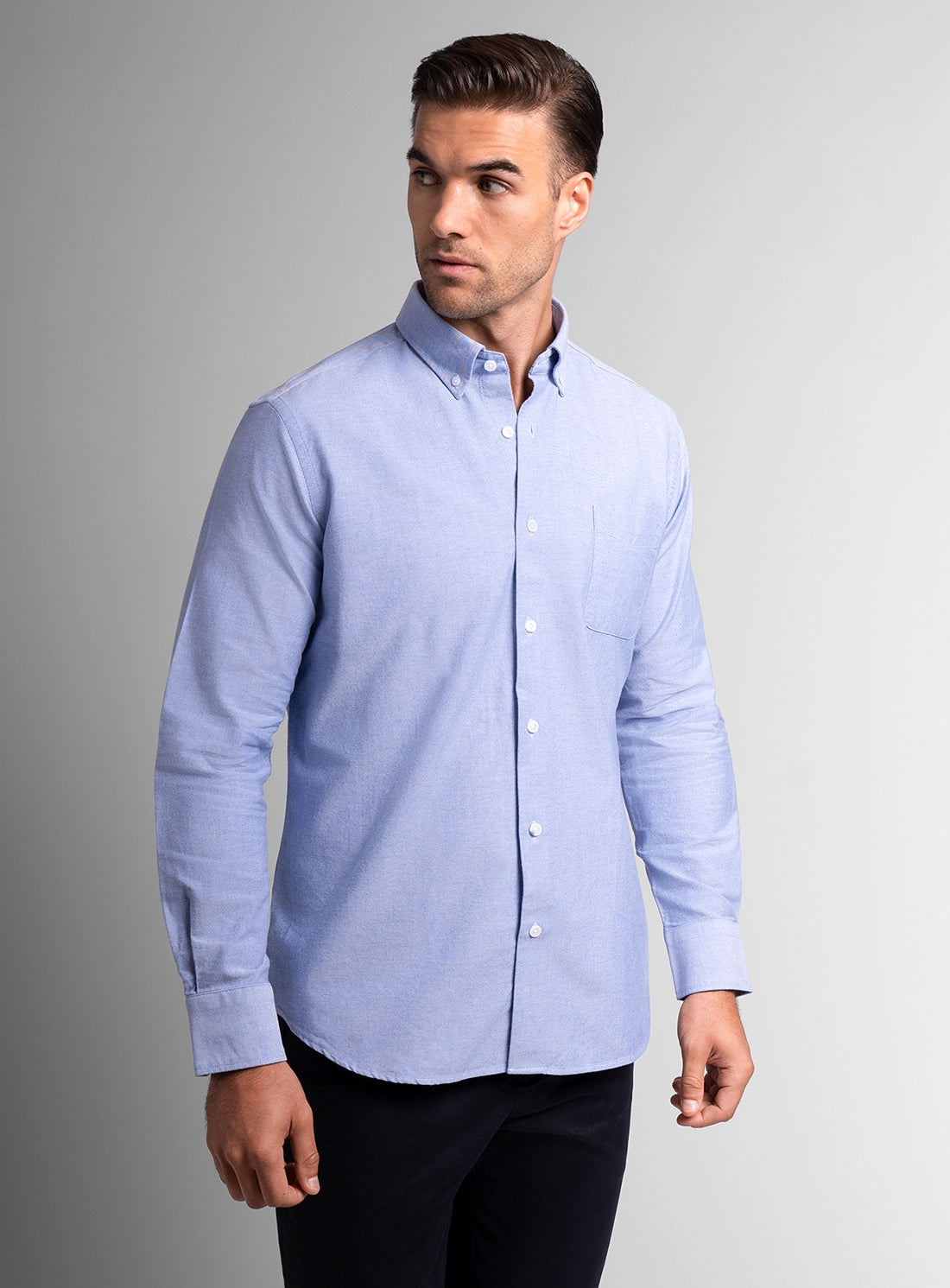 Man wearing a light blue button-up shirt against a gray background