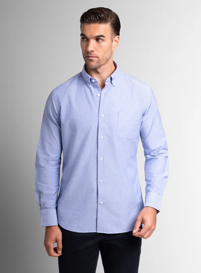 Man wearing a light blue button-up shirt against a gray background