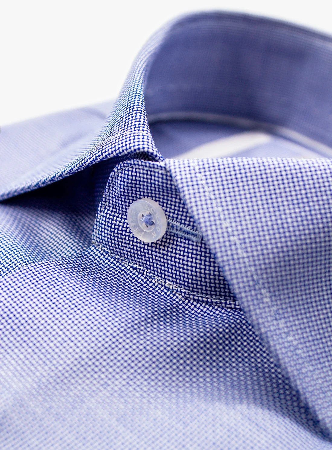 Close-up of a blue checkered shirt collar with a button.