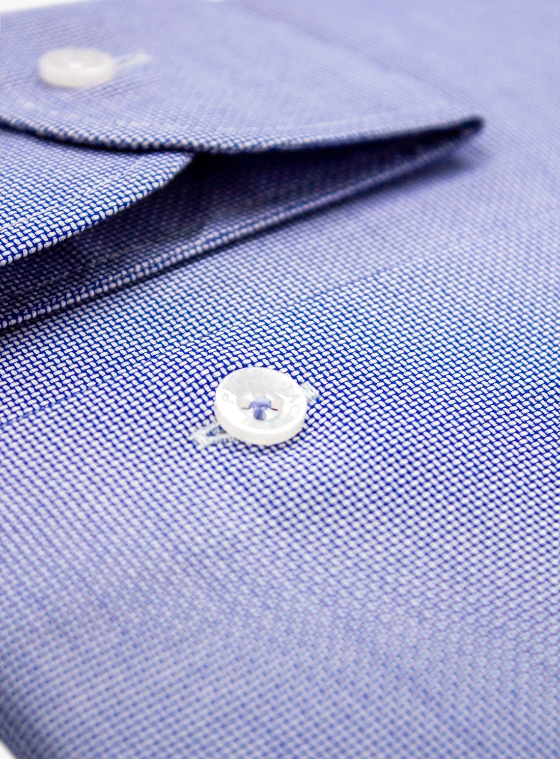 Close-up of a blue dress shirt with a button and collar detail.