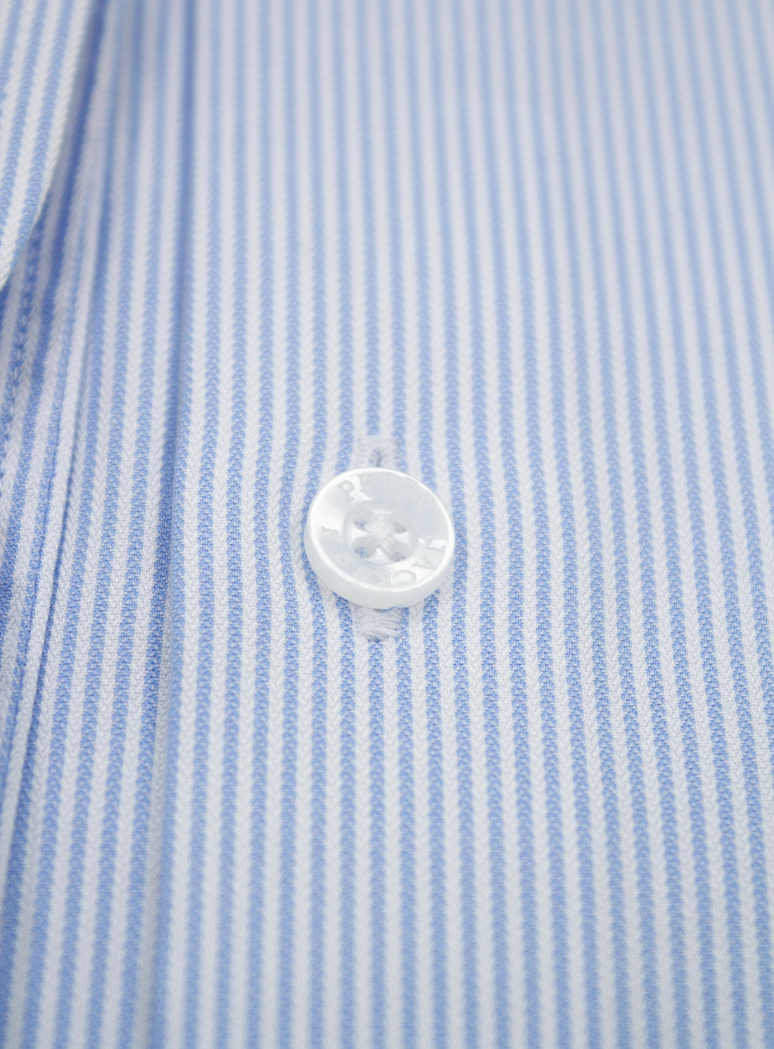 Close-up of a button on a blue and white striped shirt