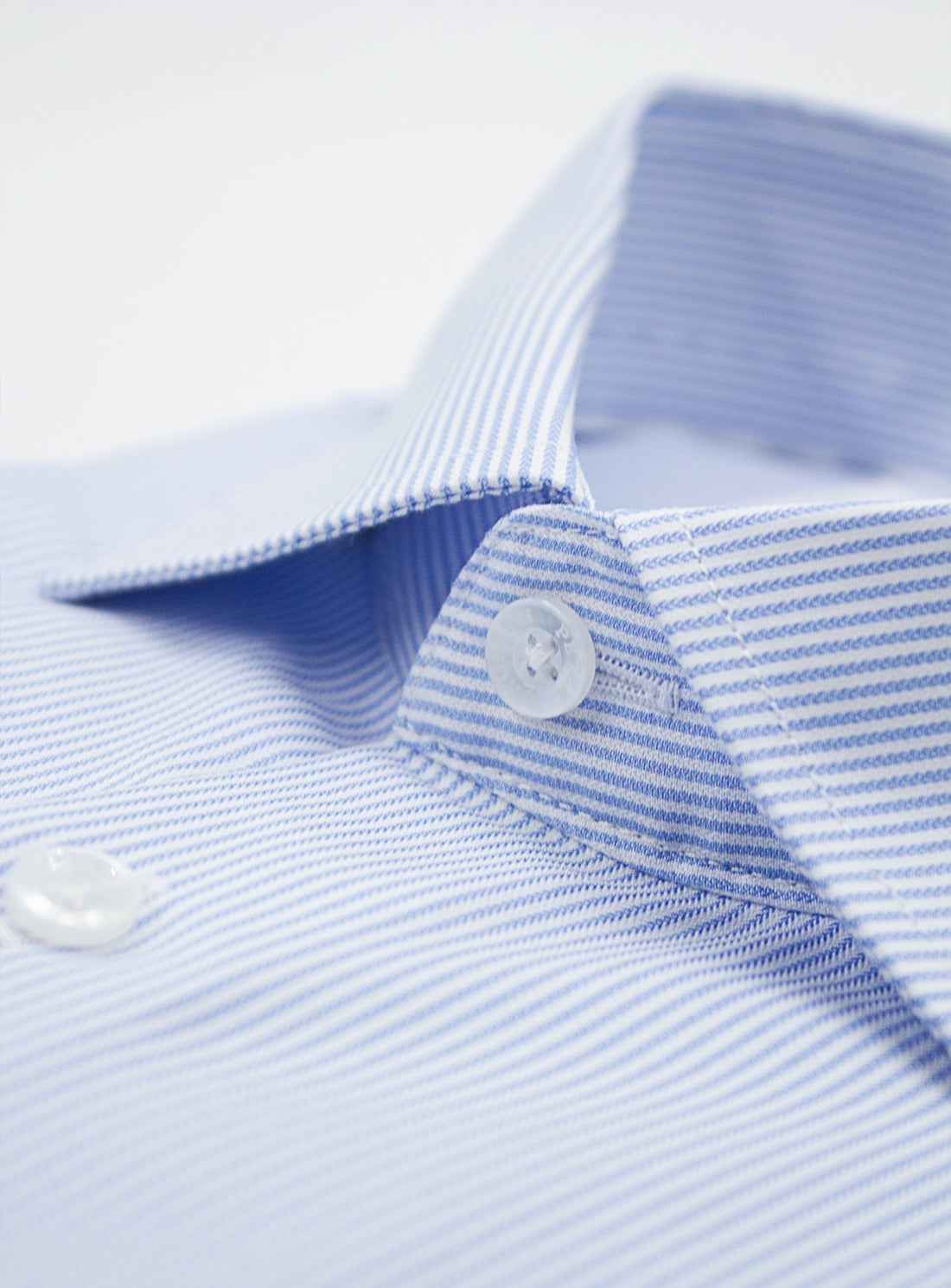 Close-up of a light blue shirt with striped collar and buttons on a white background