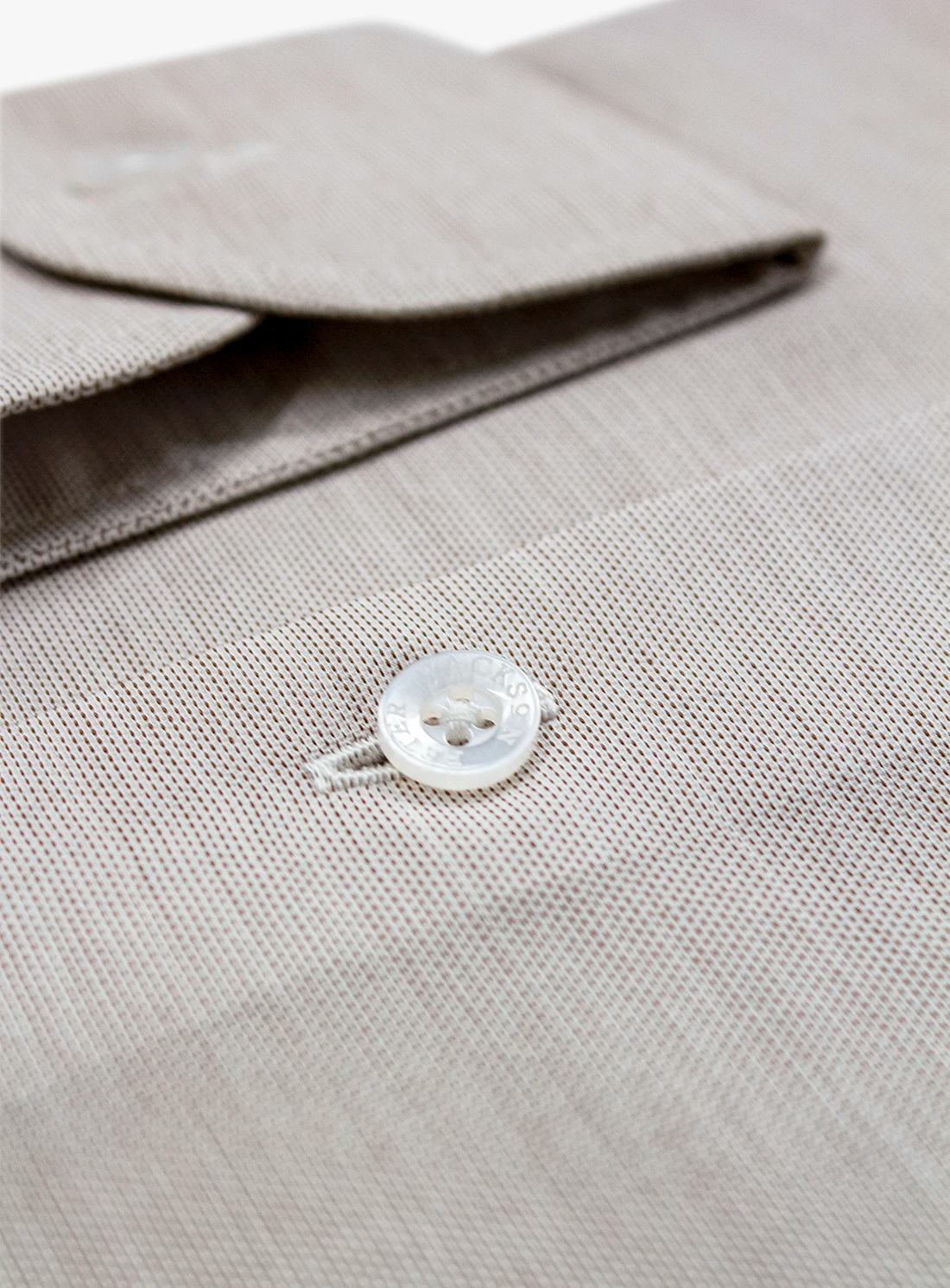 Close-up of a light gray shirt with a button on a matching fabric background