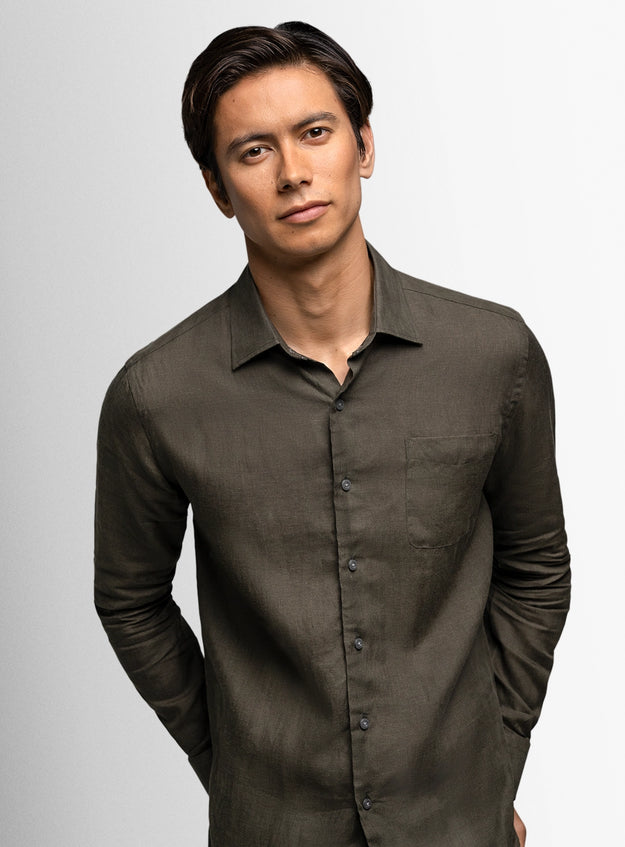 Man wearing a dark brown button-up shirt against a light gray background