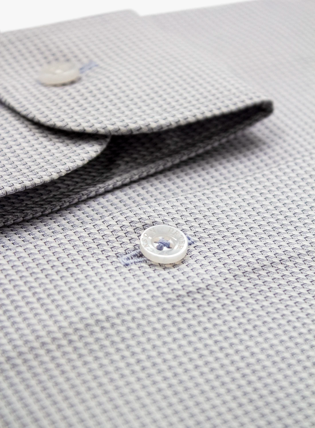 Close-up of a textured gray fabric with a button, possibly from a garment.