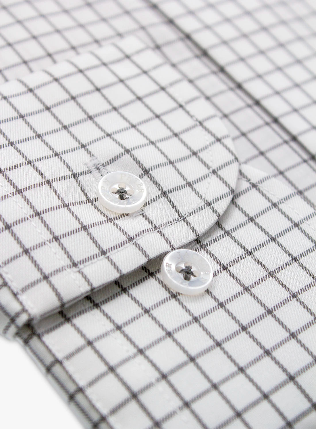 Close-up of a checkered shirt with buttons on a white background