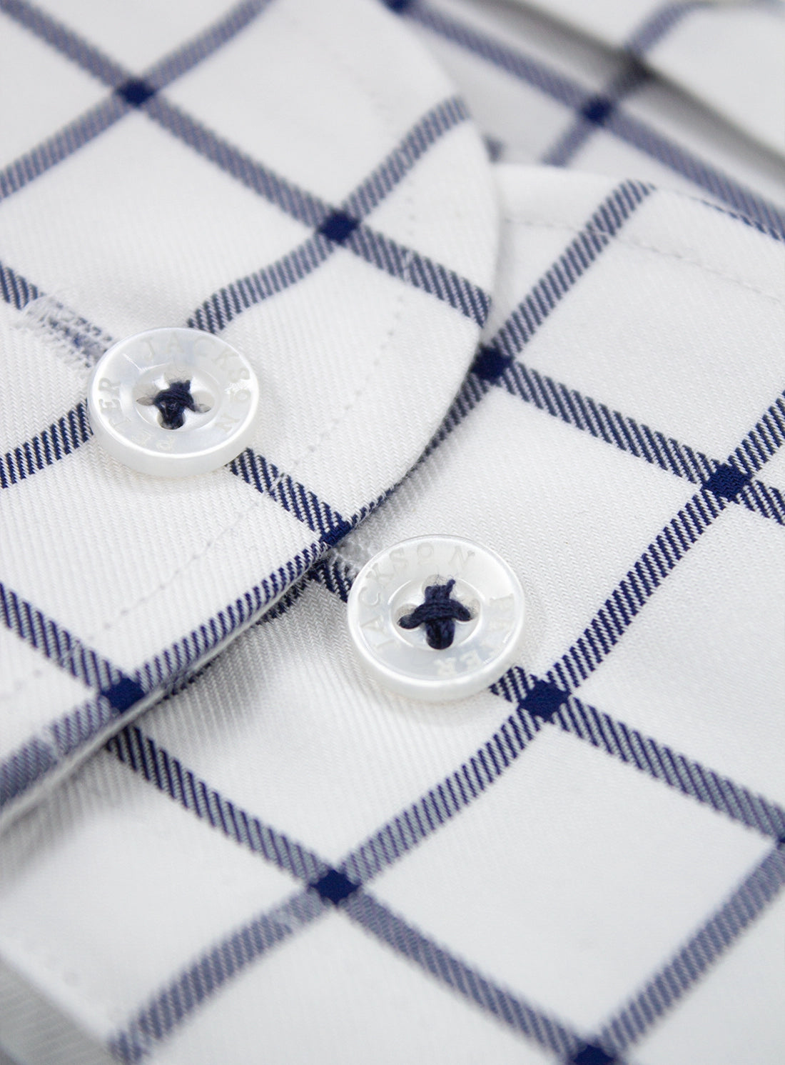 Close-up of a white shirt with blue plaid pattern and buttons.
