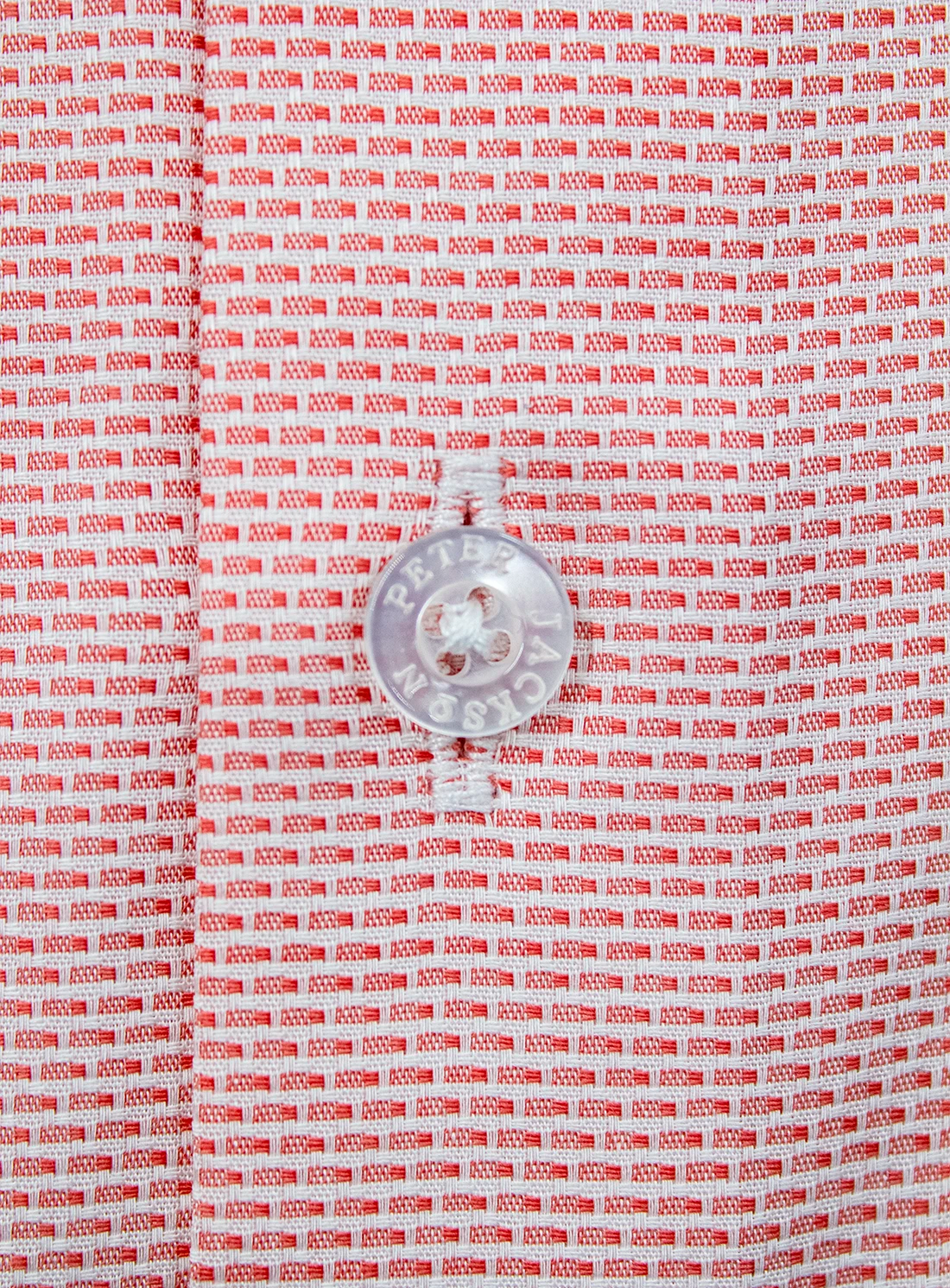 Close-up of a red and white patterned fabric with a metal button.