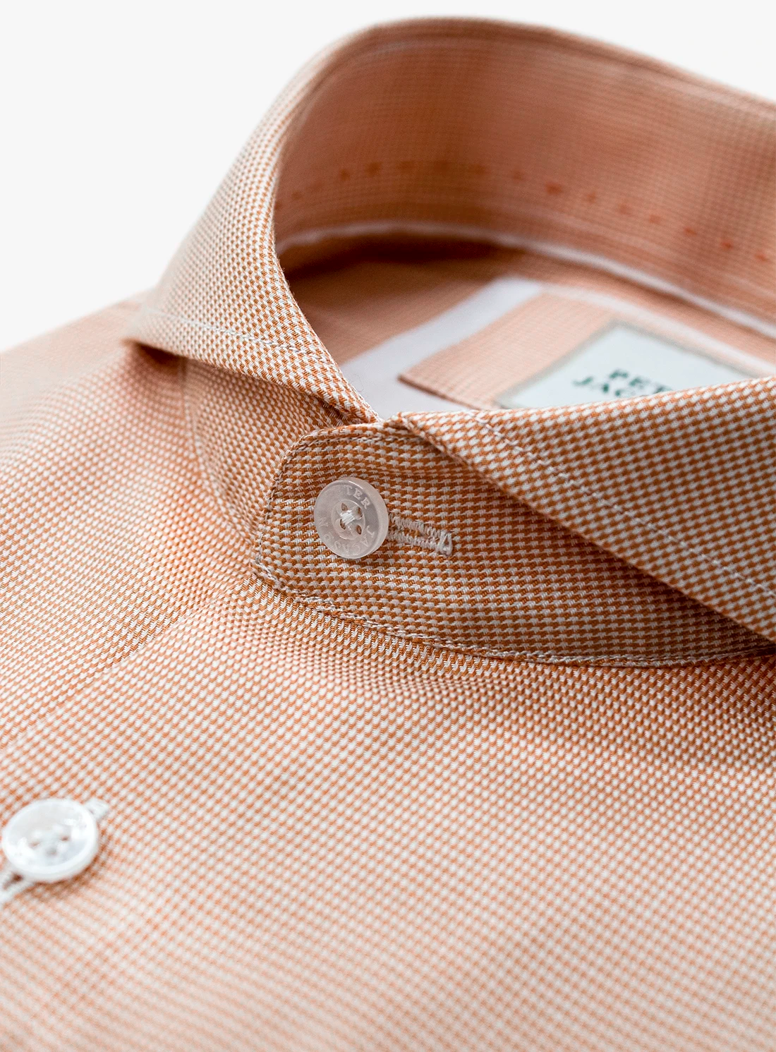 Close-up of a beige shirt collar with buttons and a label.