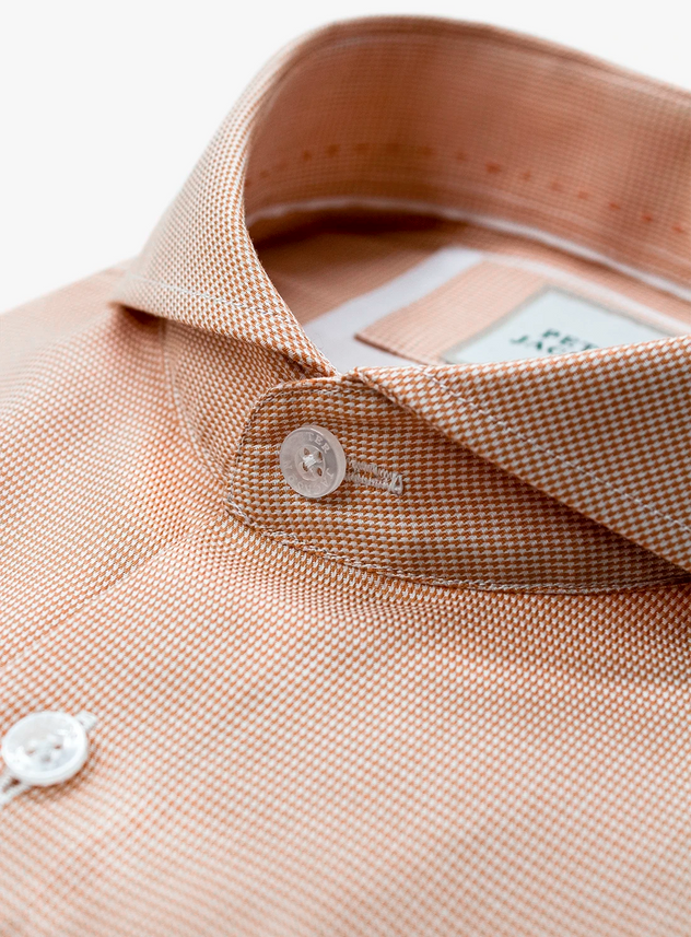 Close-up of a beige shirt collar with buttons and a label.