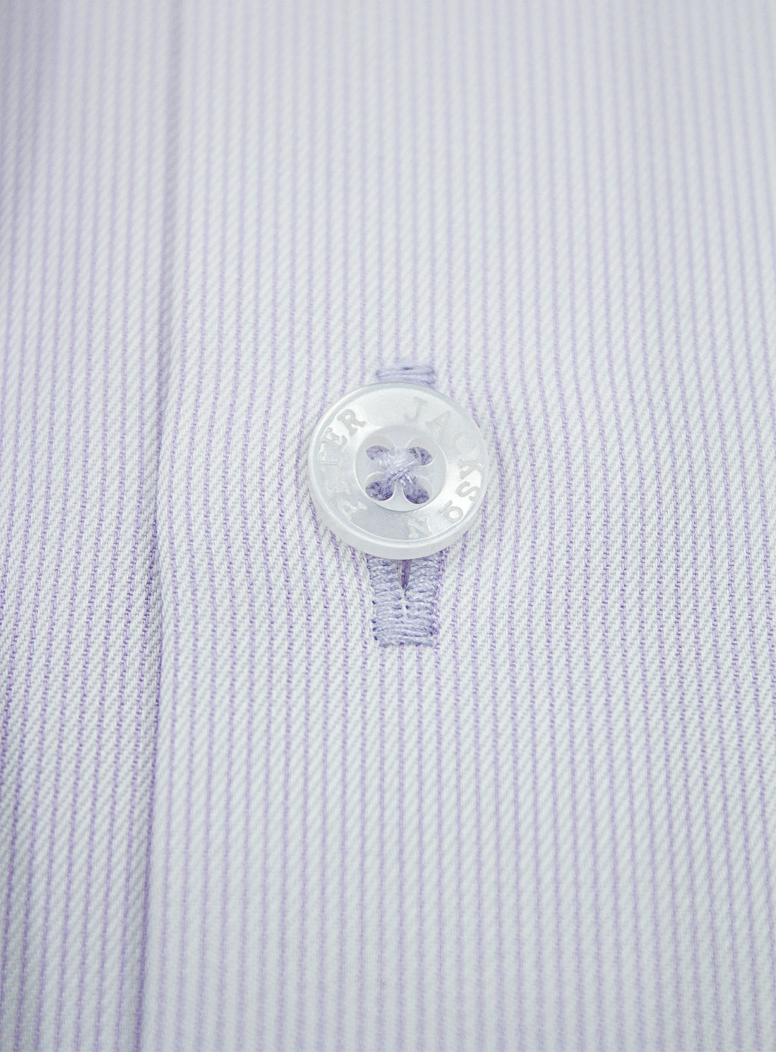 Close-up of a button on a light blue striped shirt