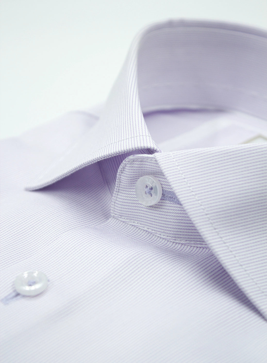 Close-up of a light purple dress shirt with button details on a white background