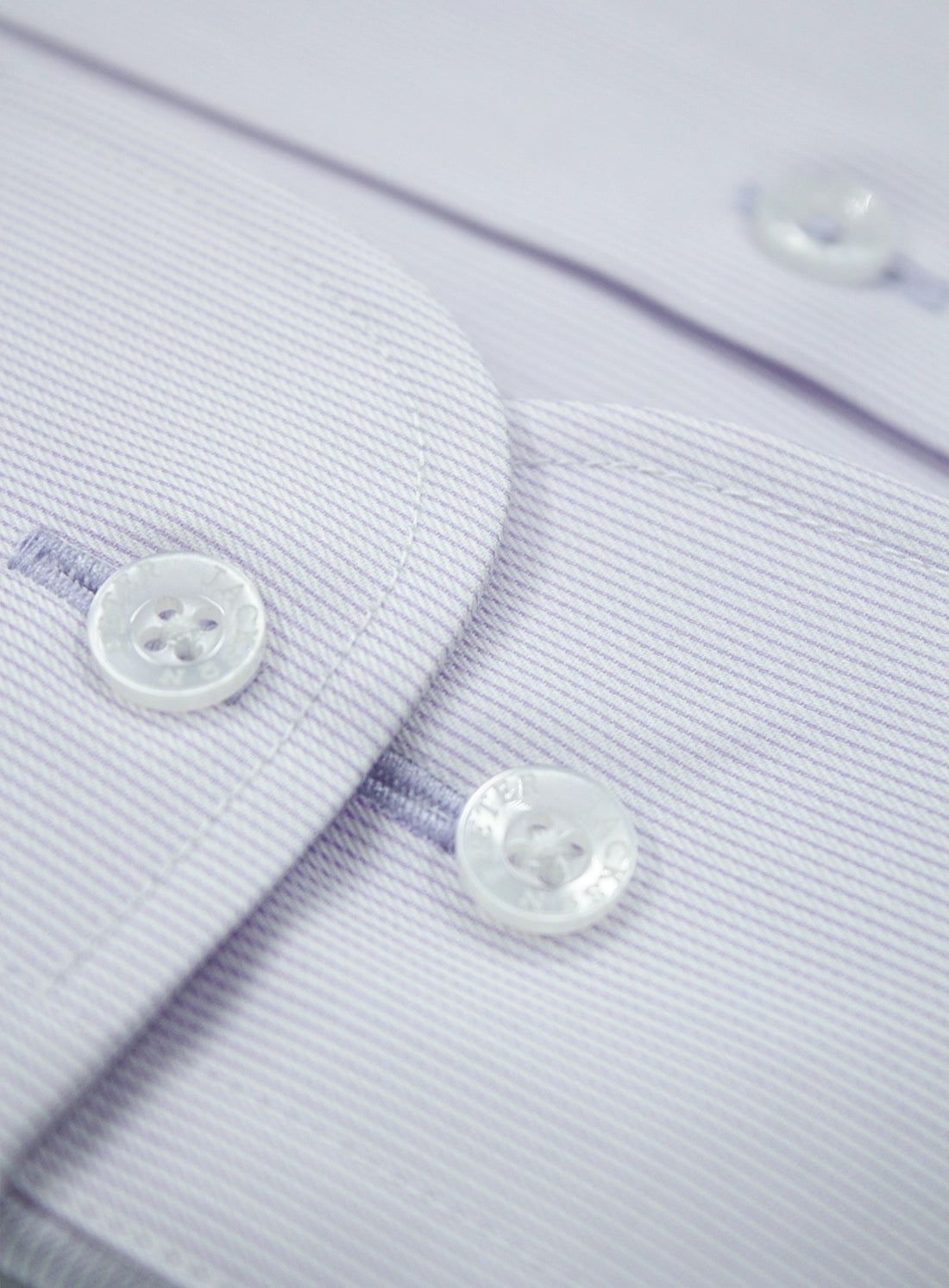 Close-up of a light purple shirt with buttons on a matching fabric background