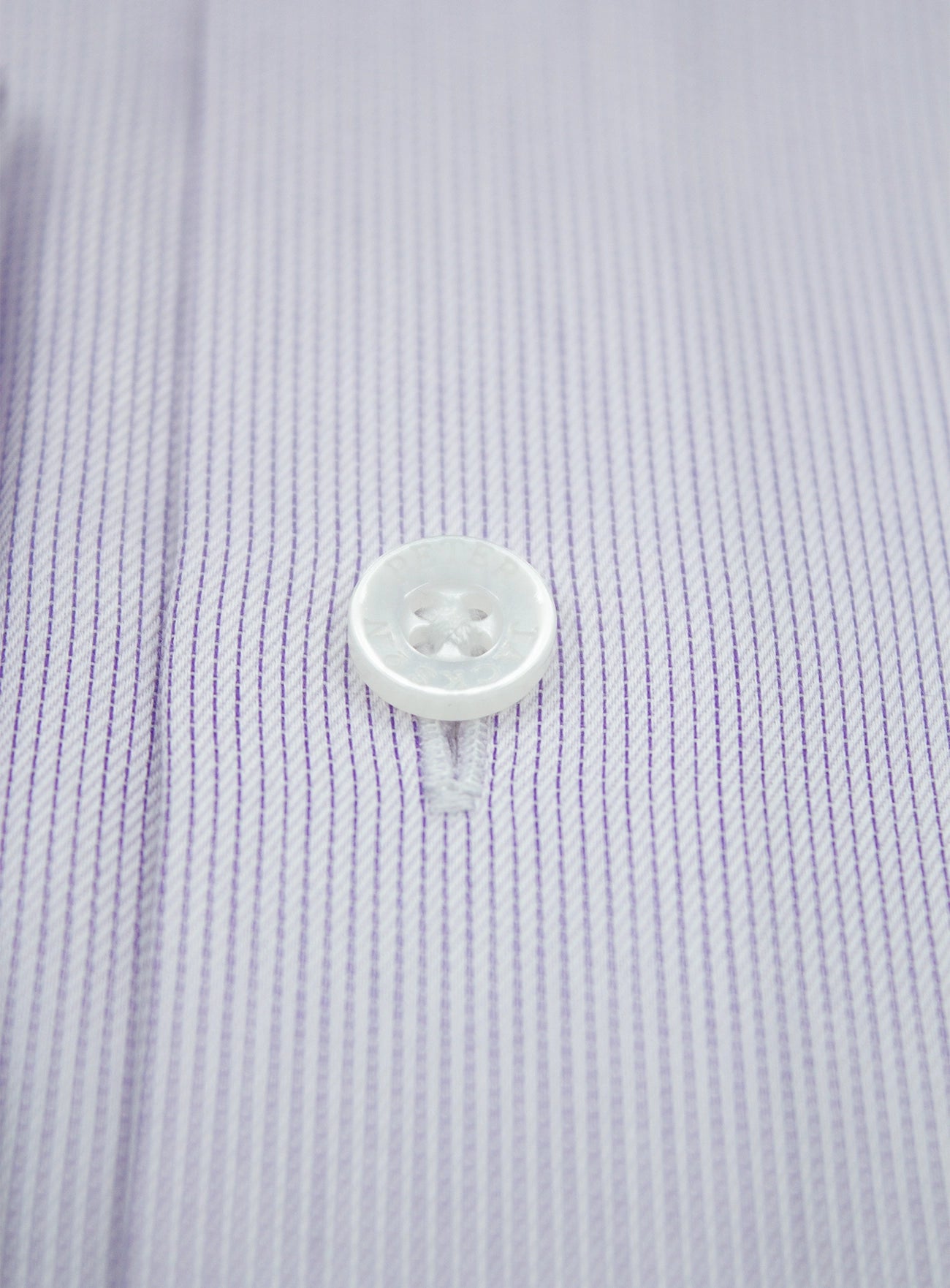 Close-up of a button on a light purple textured fabric