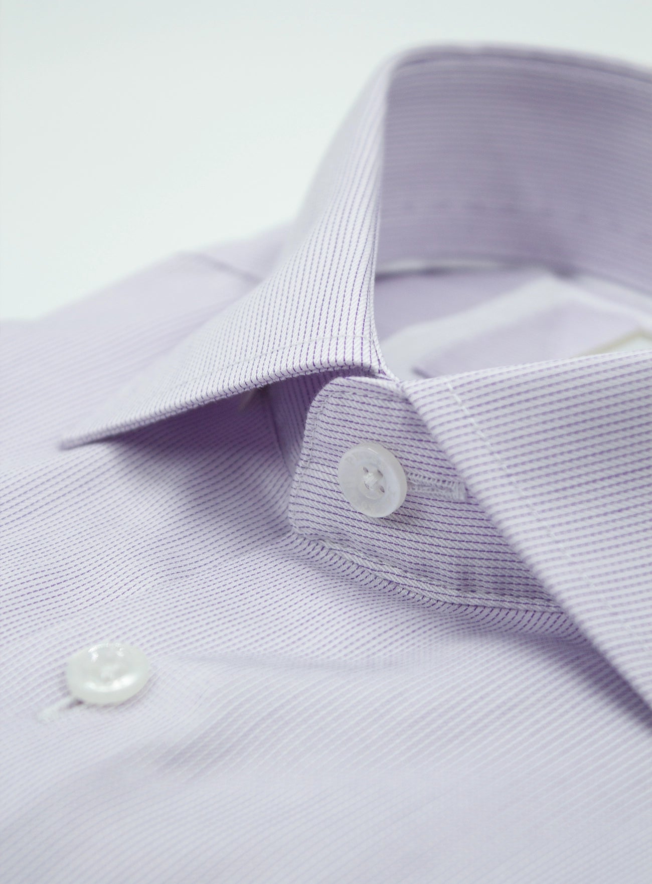 Close-up of a light purple dress shirt with collar and buttons on a white background