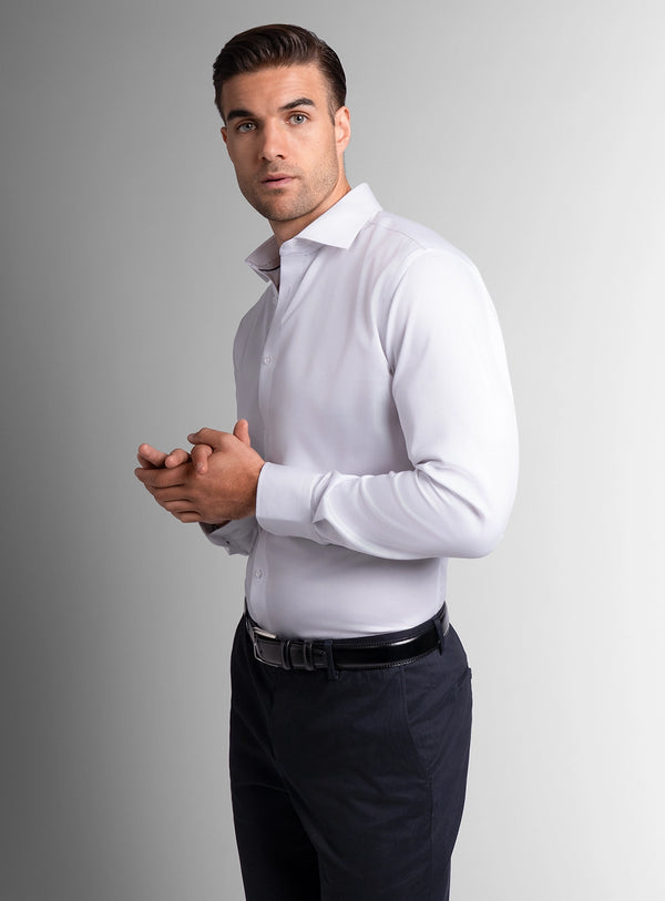 Man wearing a white dress shirt and dark pants against a gray background