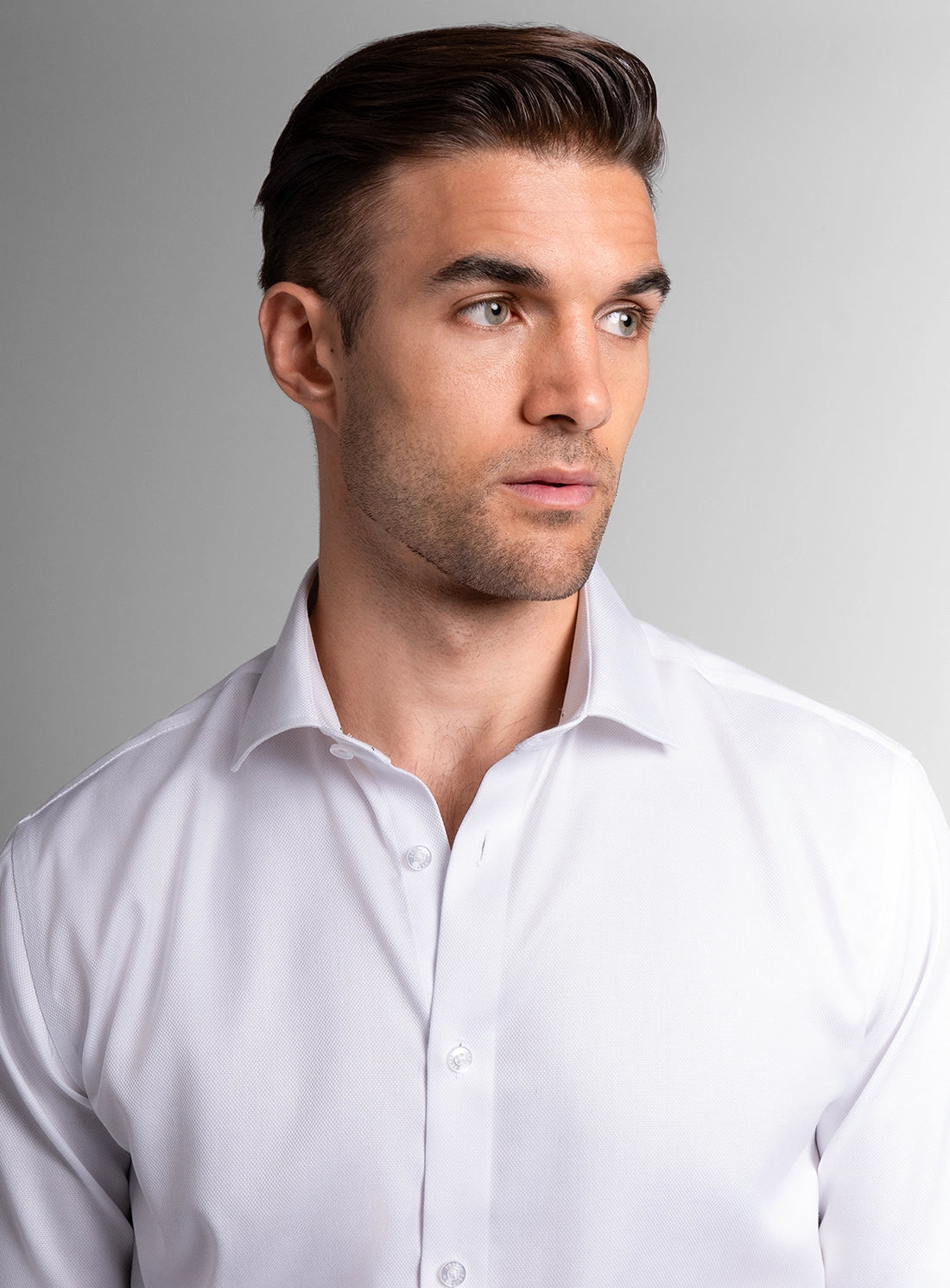 Man wearing a white dress shirt against a gray background