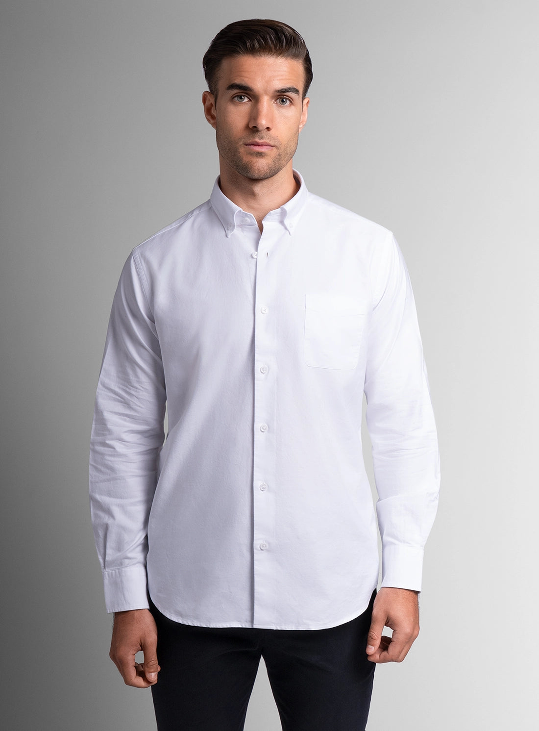 Man wearing a white dress shirt against a gray background