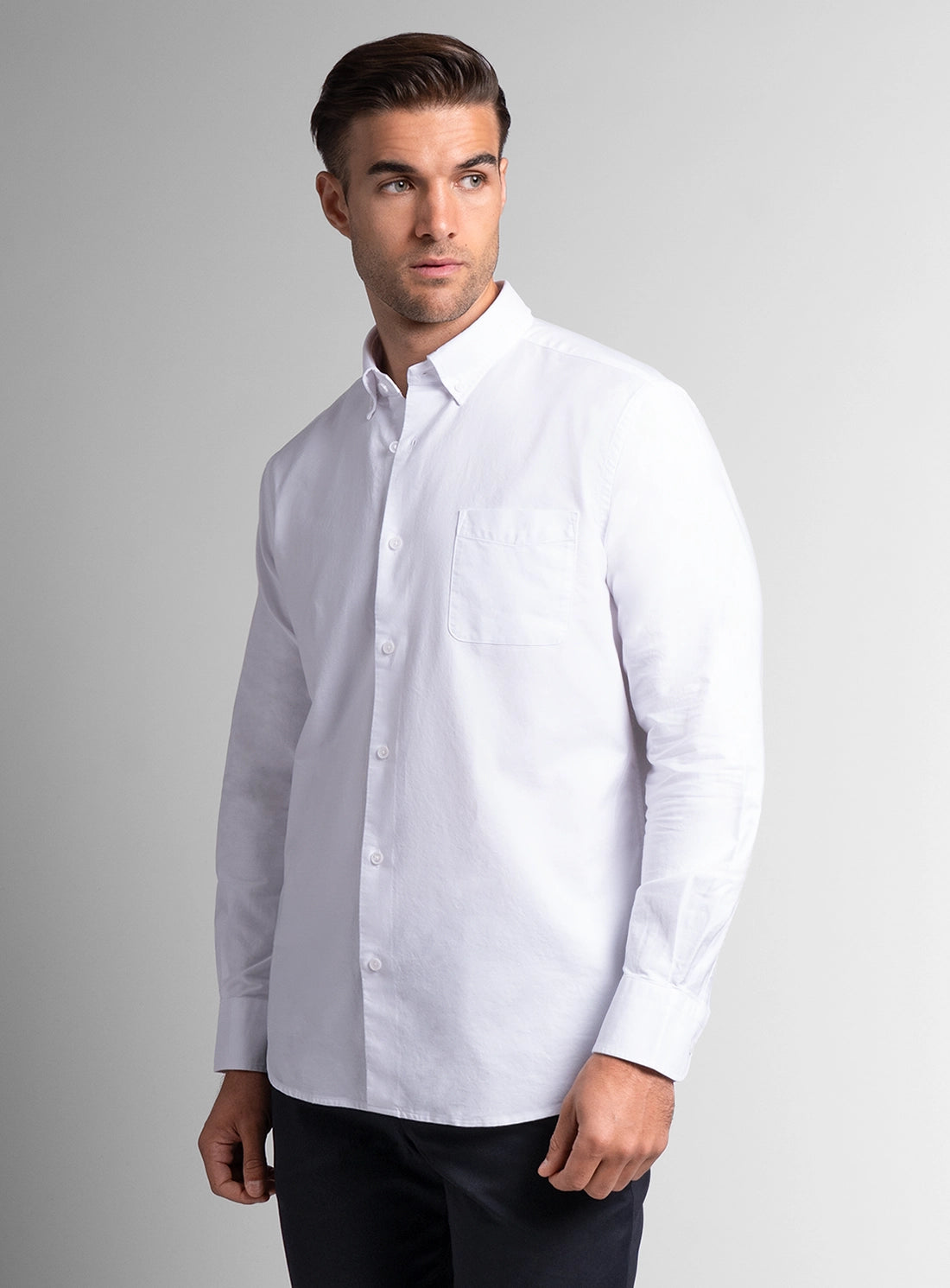 Man wearing a white dress shirt against a gray background