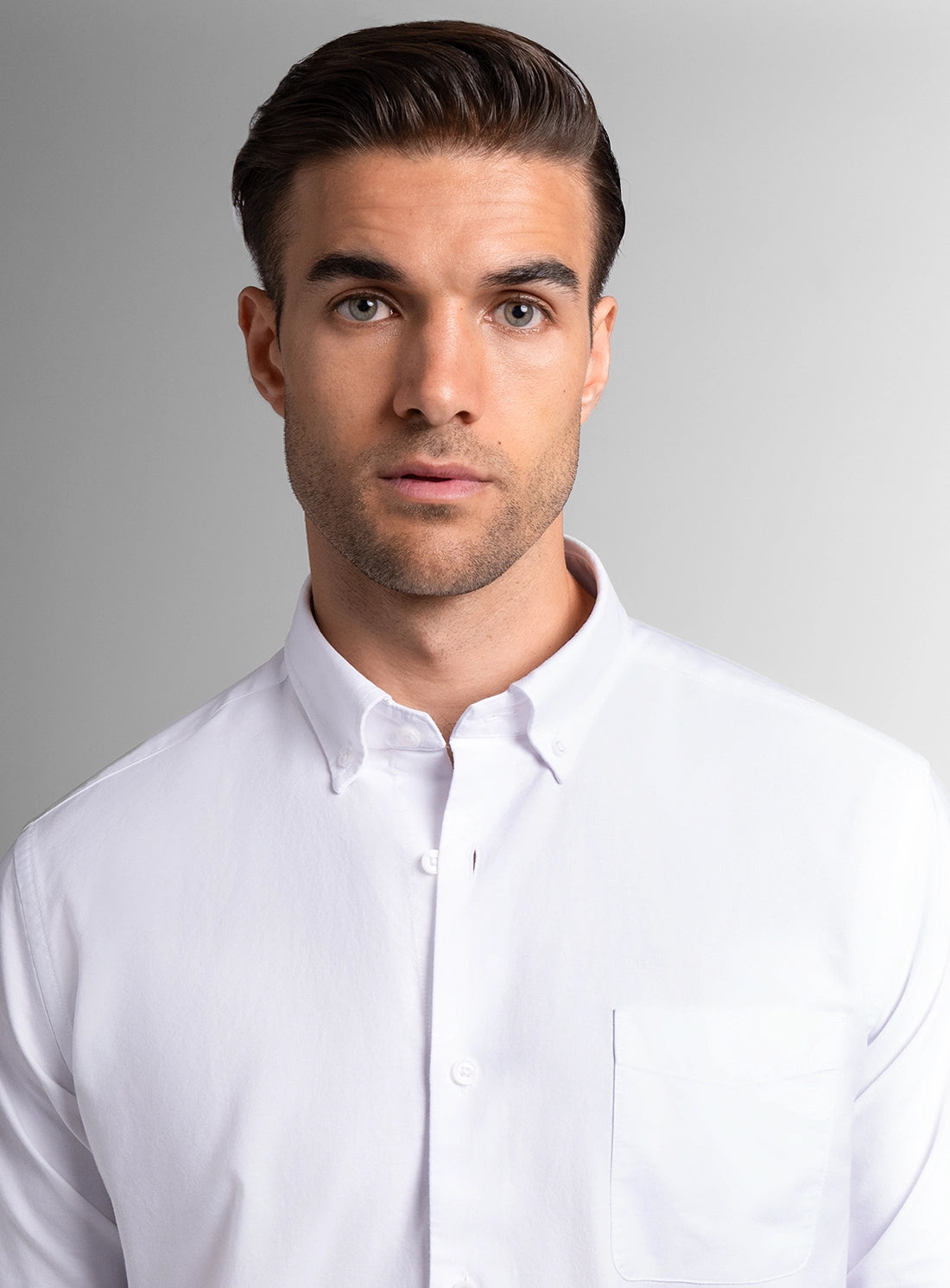 Man wearing a white dress shirt against a gray background