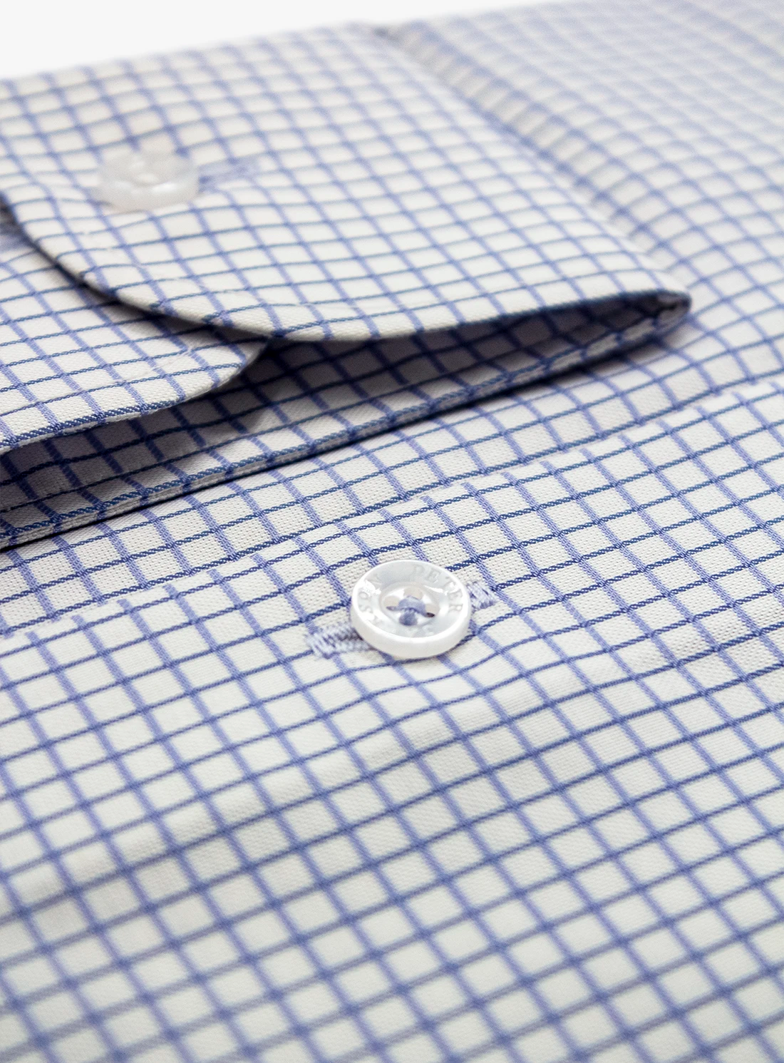 Close-up of a blue and white checkered shirt with a button.
