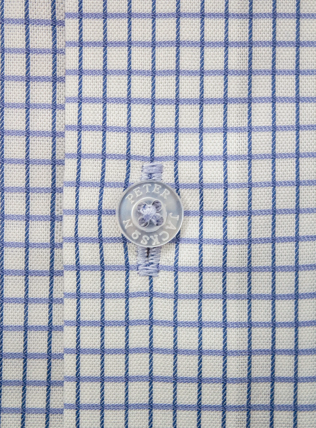 Close-up of a shirt button on a blue and white checkered fabric
