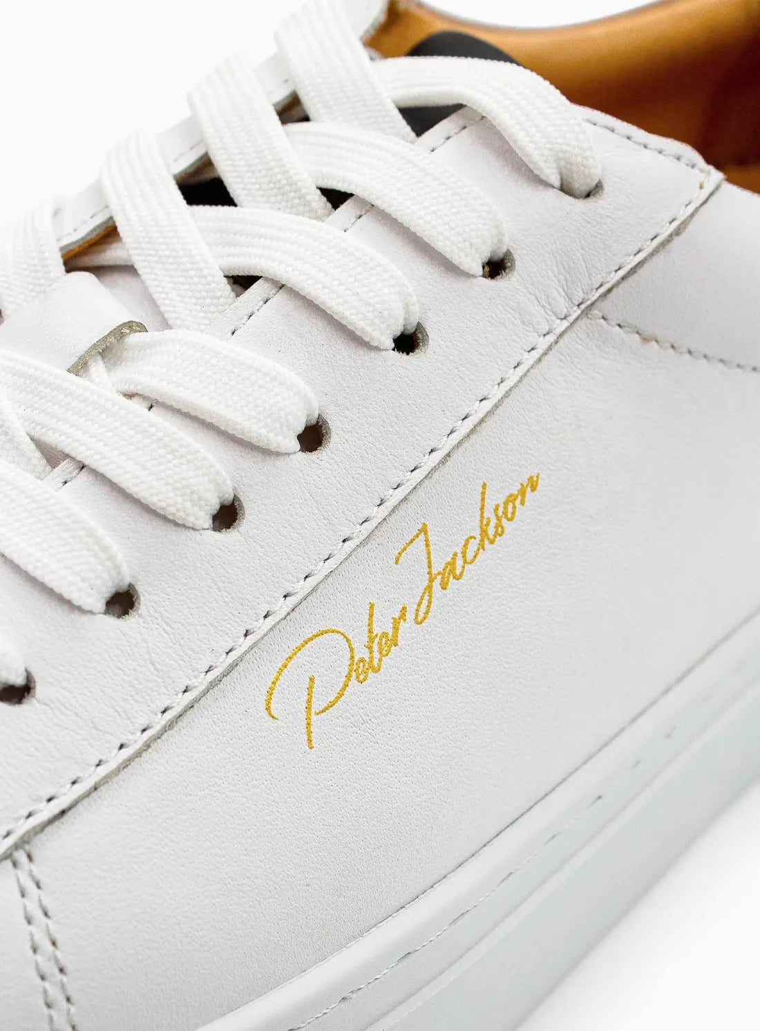 White sneaker with gold 'Peter Jackson' branding on a white background