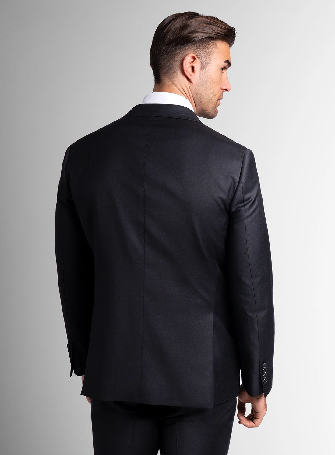 Man wearing a black suit jacket on a gray background