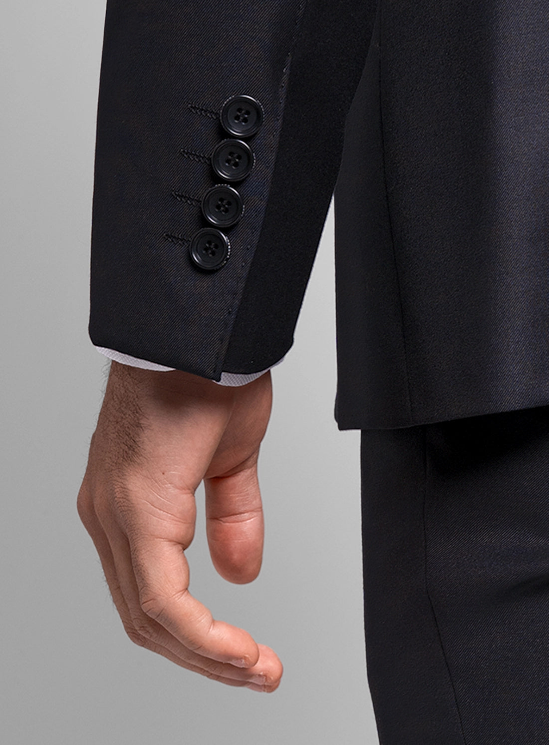 Close-up of a black suit jacket with three buttons on a gray background