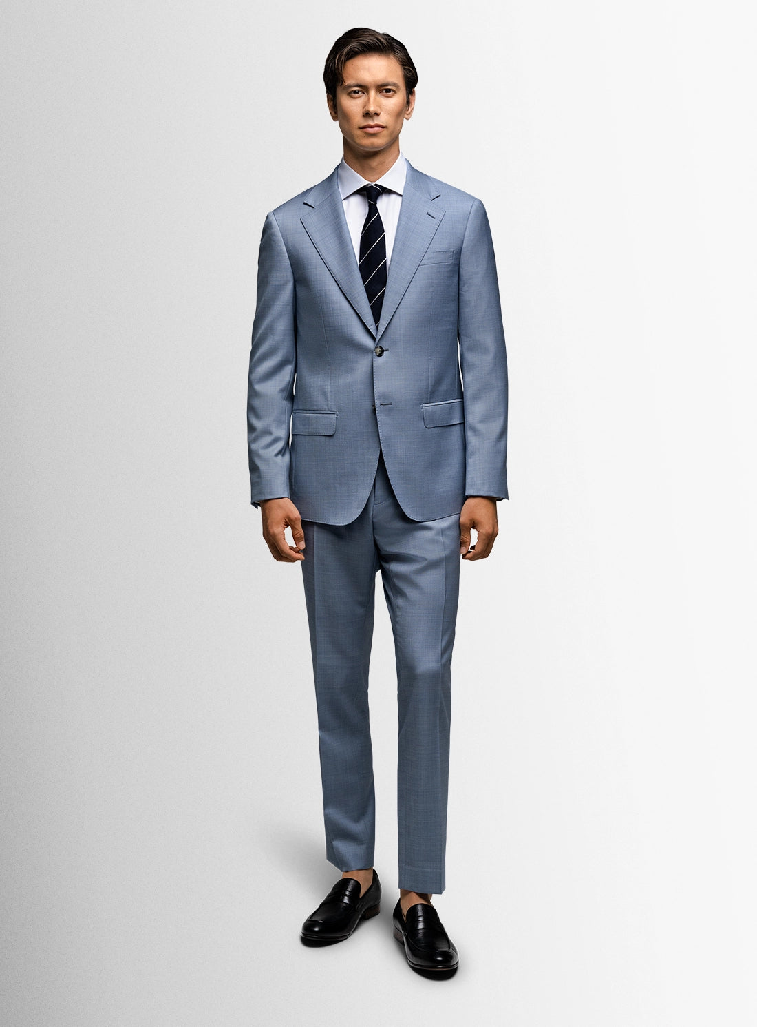 Man wearing a light blue suit with a striped tie on a white background