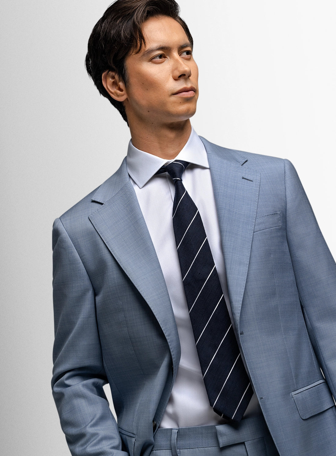 Man wearing a gray suit with a striped tie against a plain background