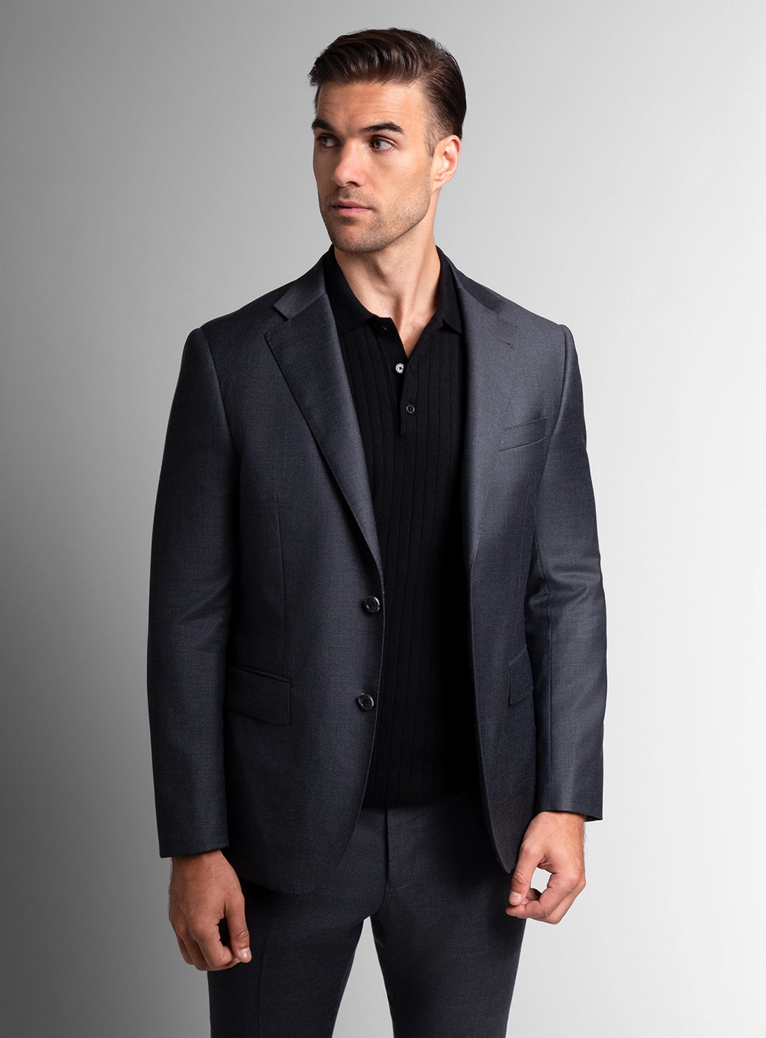 Man wearing a dark gray suit against a gray background