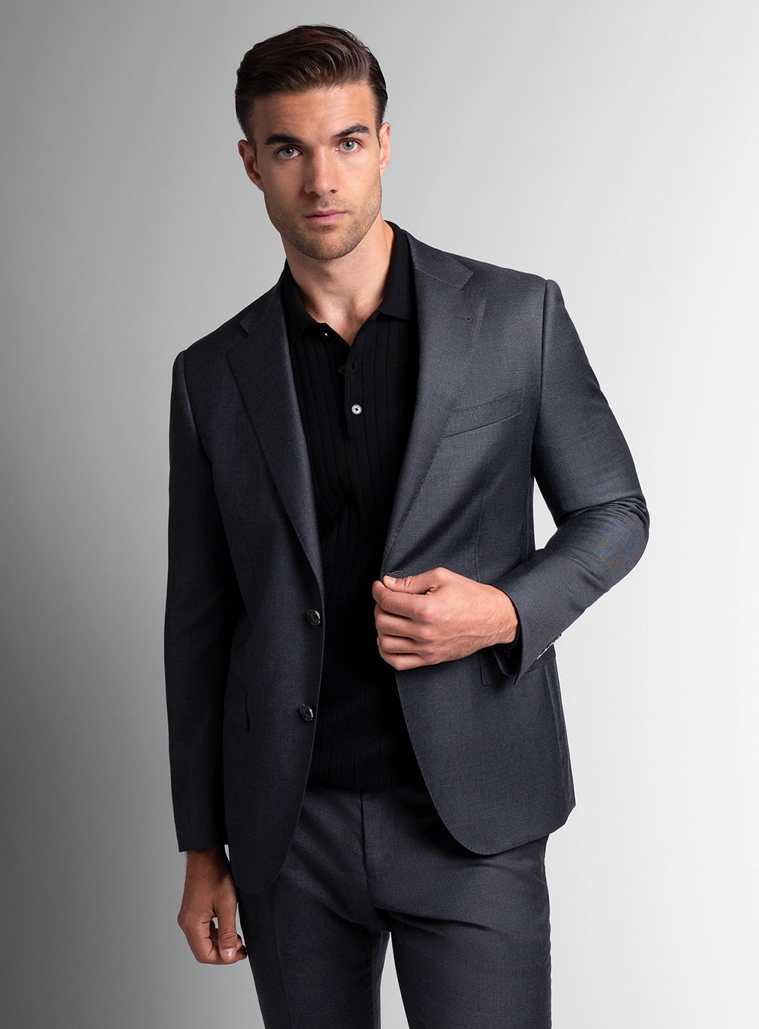 Man wearing a dark gray suit against a gradient background