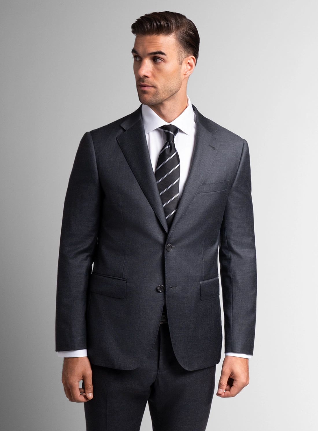Man wearing a gray suit with a striped tie on a gray background