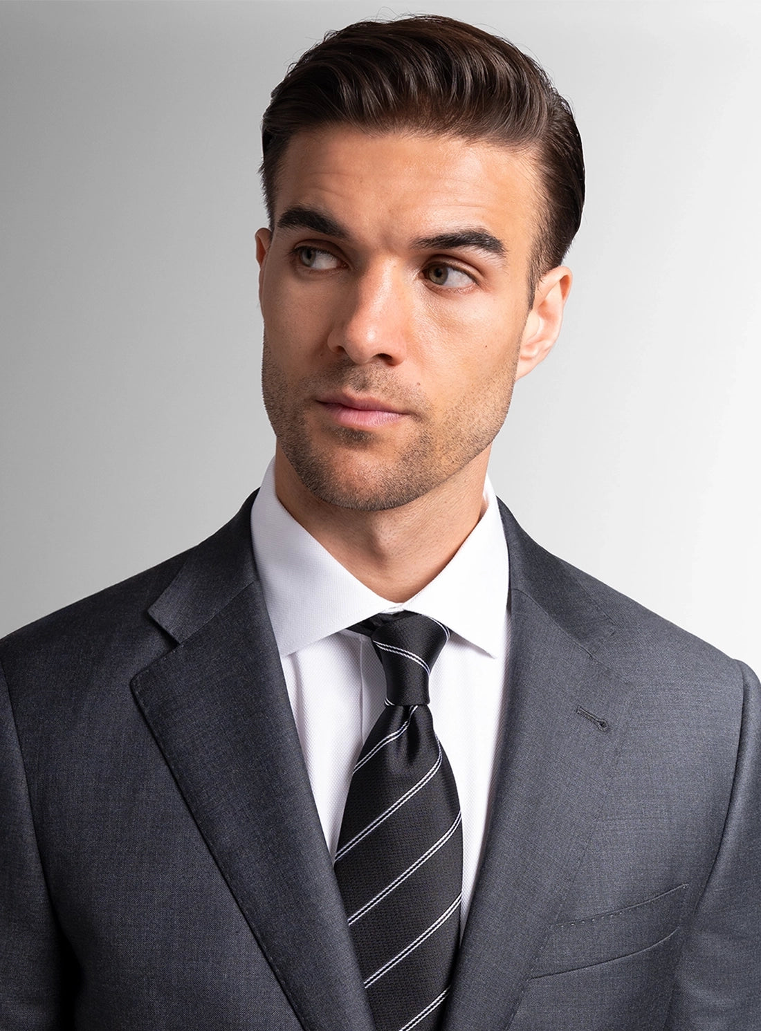 Man wearing a gray suit with a striped tie against a plain background