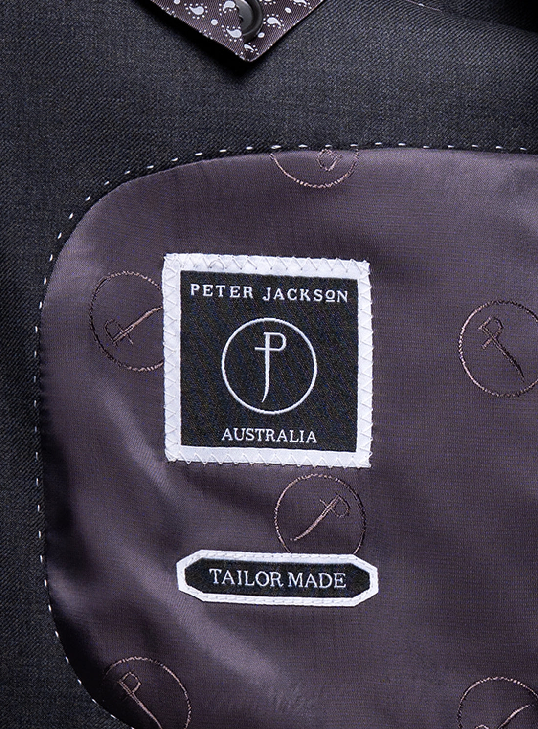 Close-up of a 'Peter Jackson Australia' tailor-made label on a dark fabric background.
