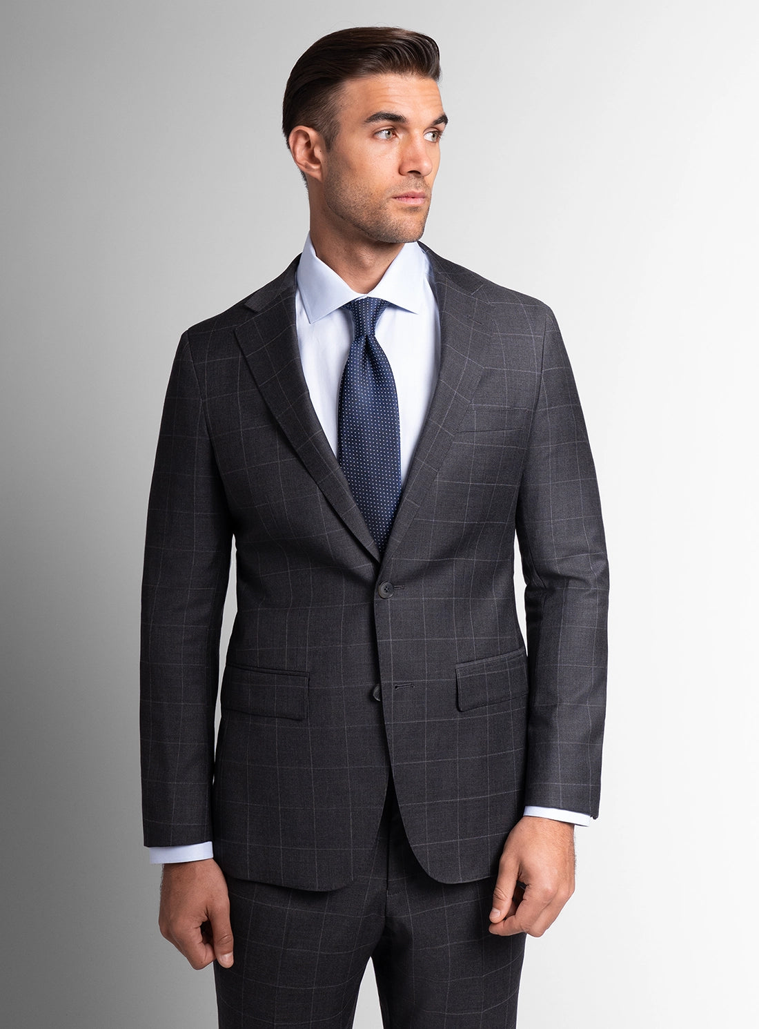 Man wearing a gray checkered suit with a blue tie on a gray background