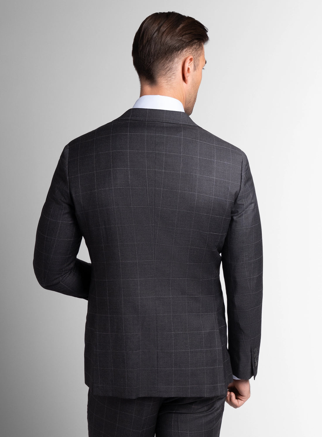 Man wearing a gray checkered suit jacket on a light gray background