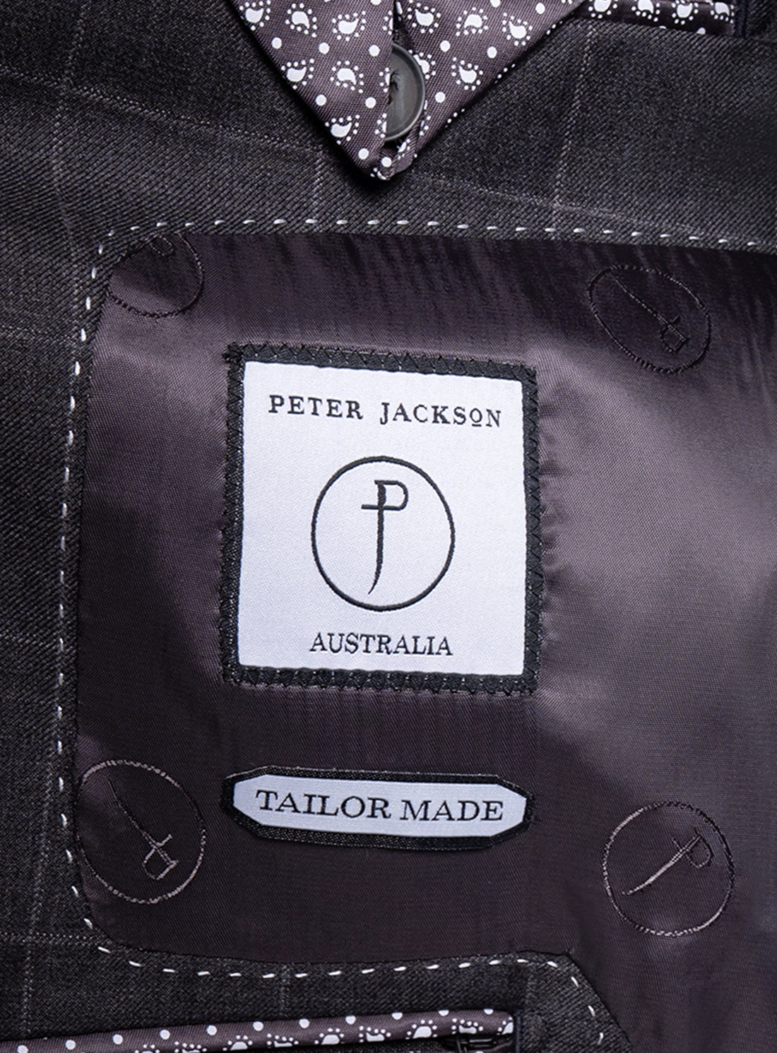 Close-up of a suit label with 'Peter Jackson Australia' branding on a black suit jacket.