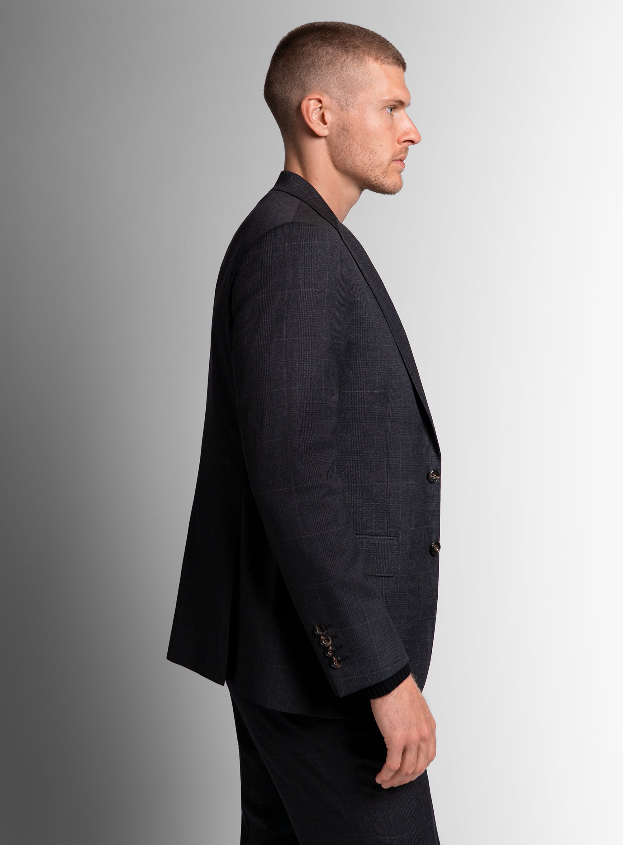 Man wearing charcoal grey suit standing to the side