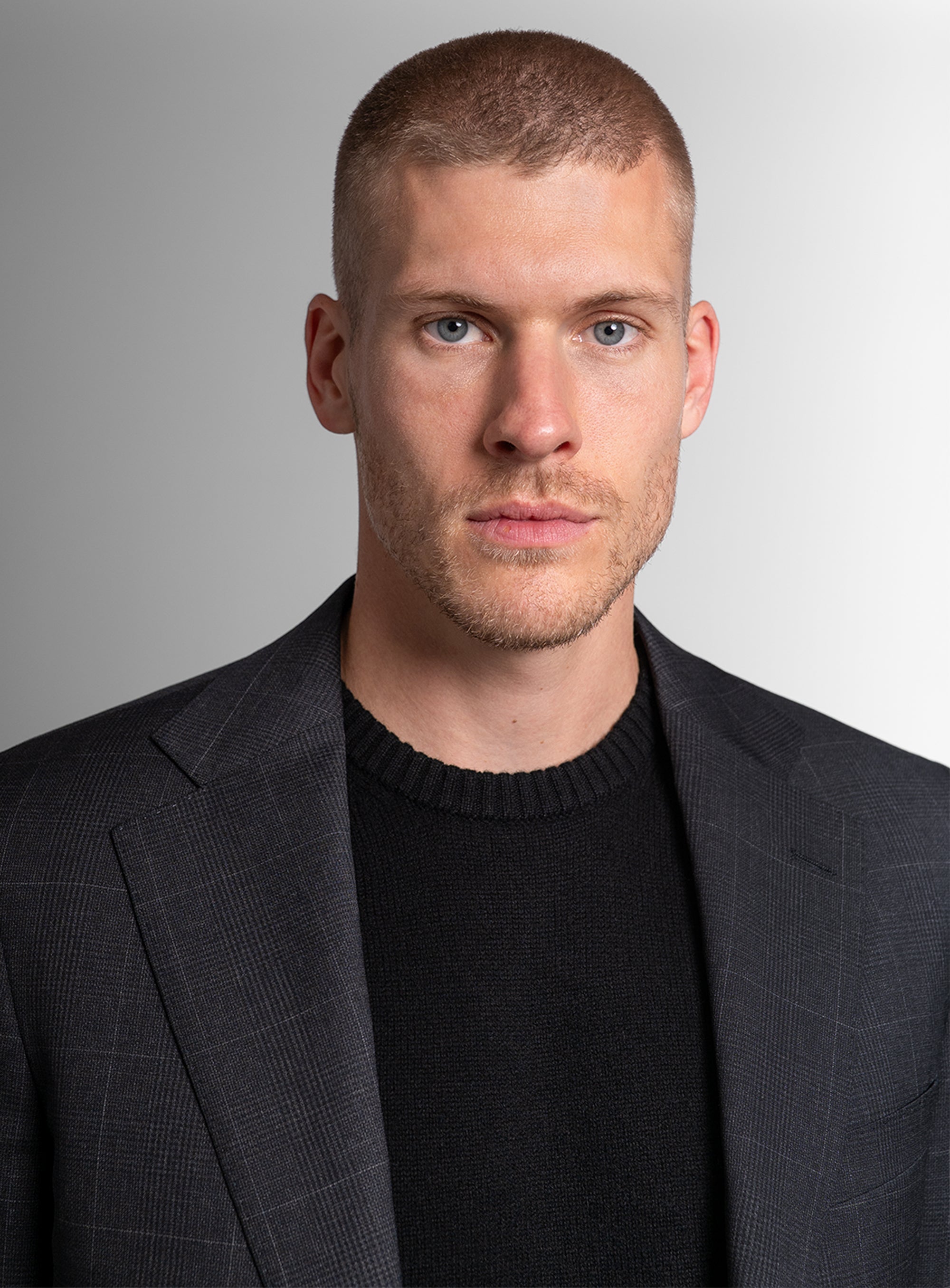 Close up of man wearing charcoal grey suit with black shirt