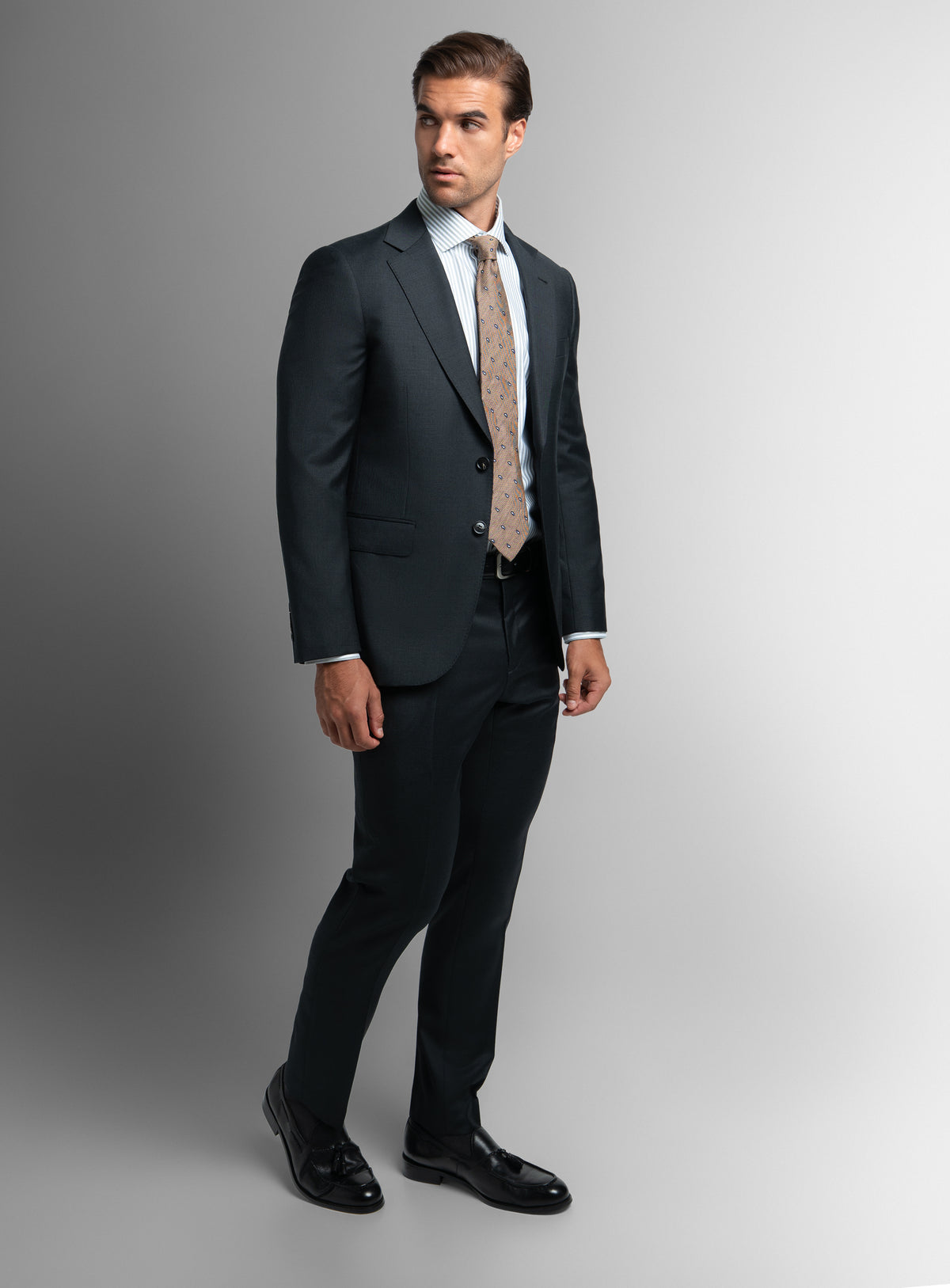 A man posing while wearing the Brunello Twill Charcoal Grey Suit