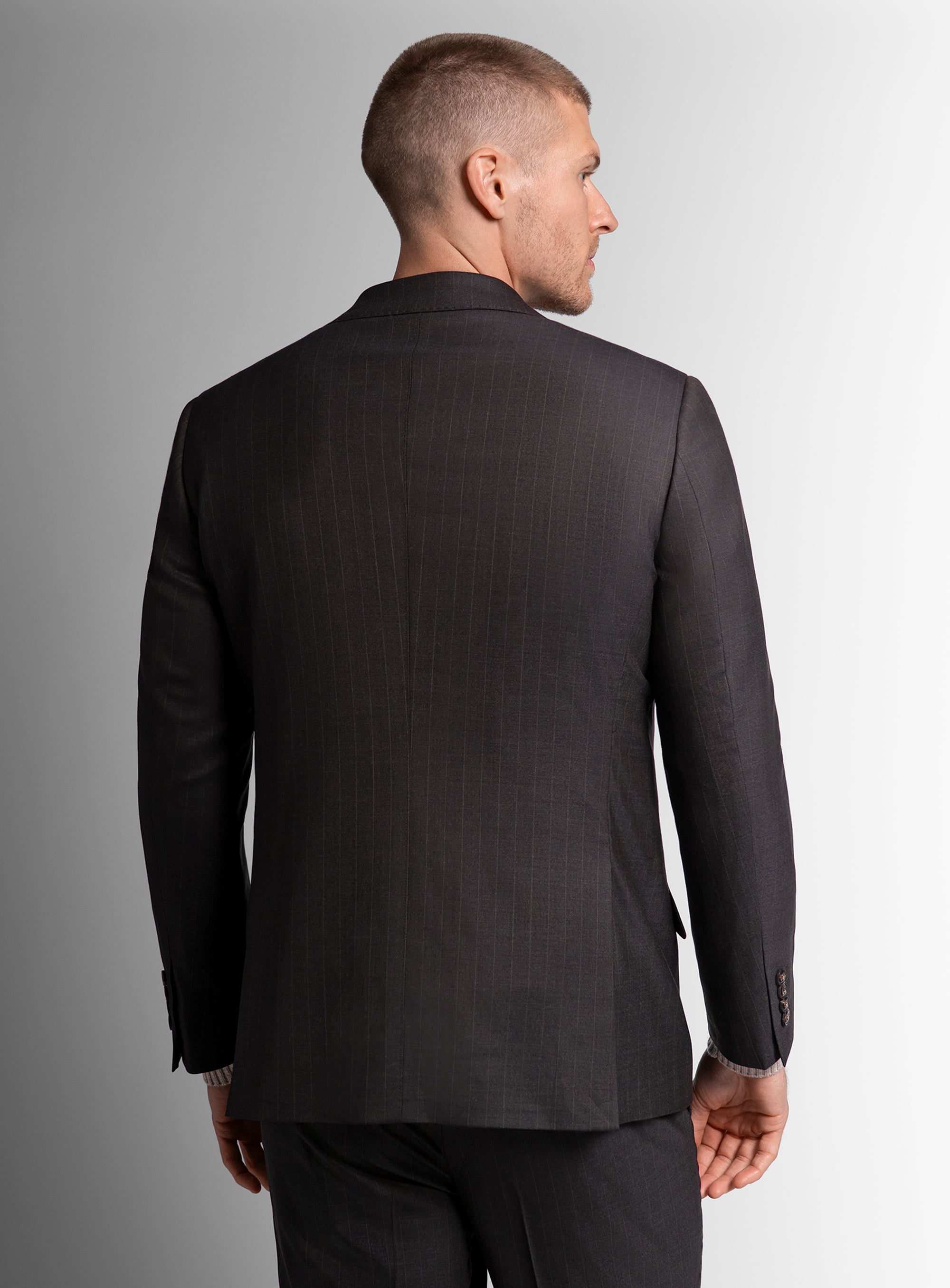 Man wearing a bronw suit jacket on a gray background