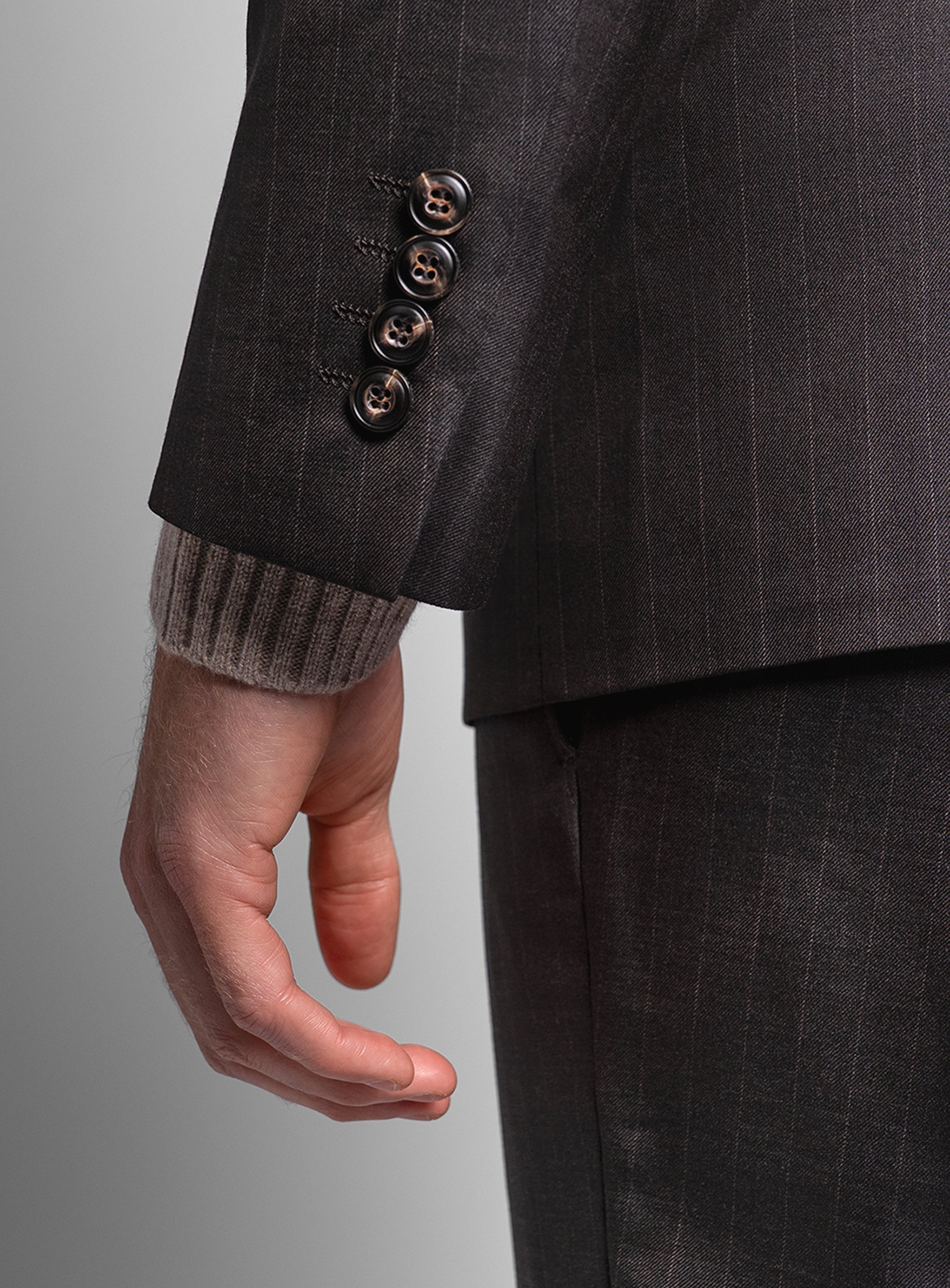 Close-up of a brown suit wearing a textured sleeve against a gray background