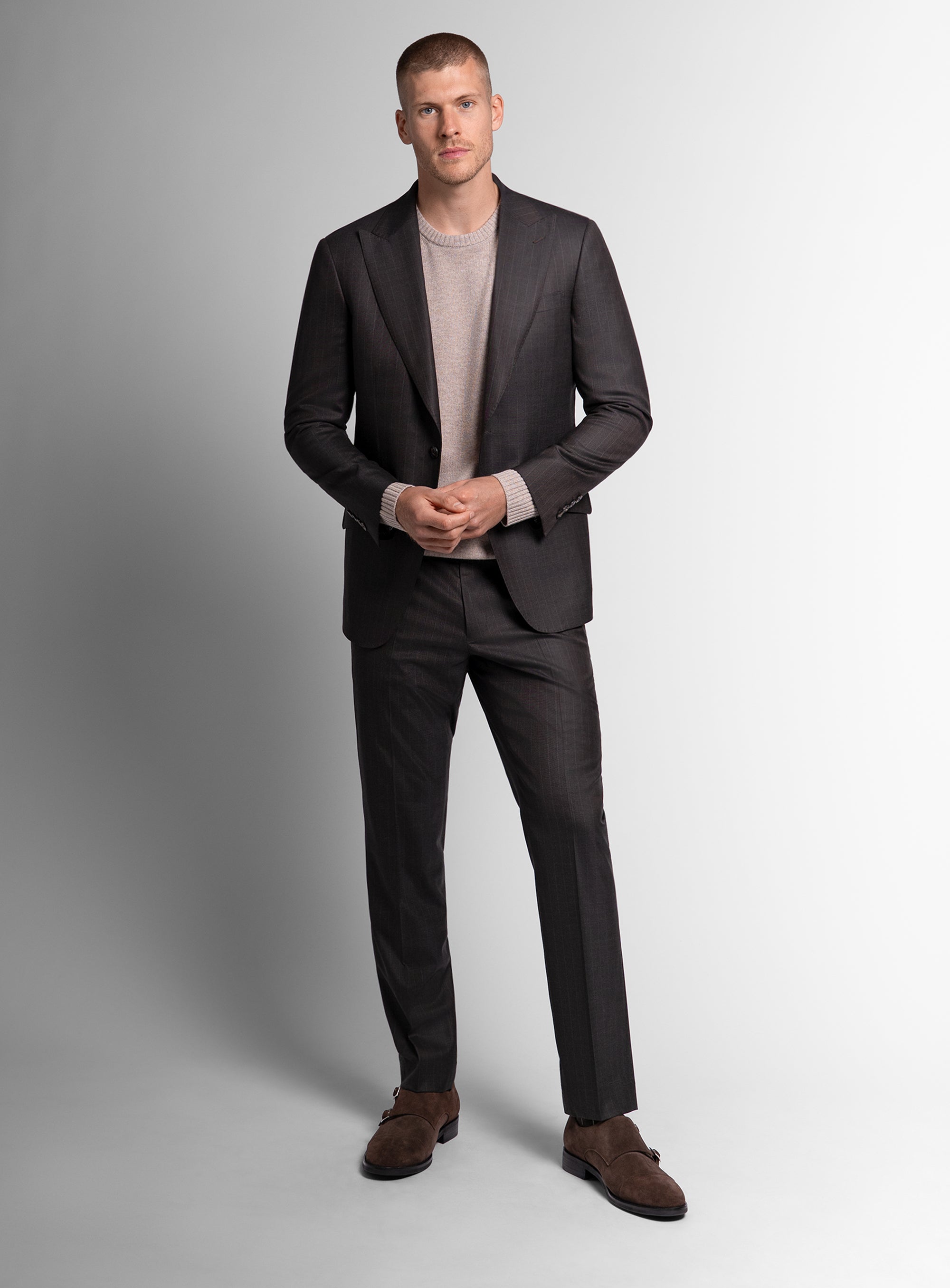 Man wearing a brown suit with a light gray shirt on a white background